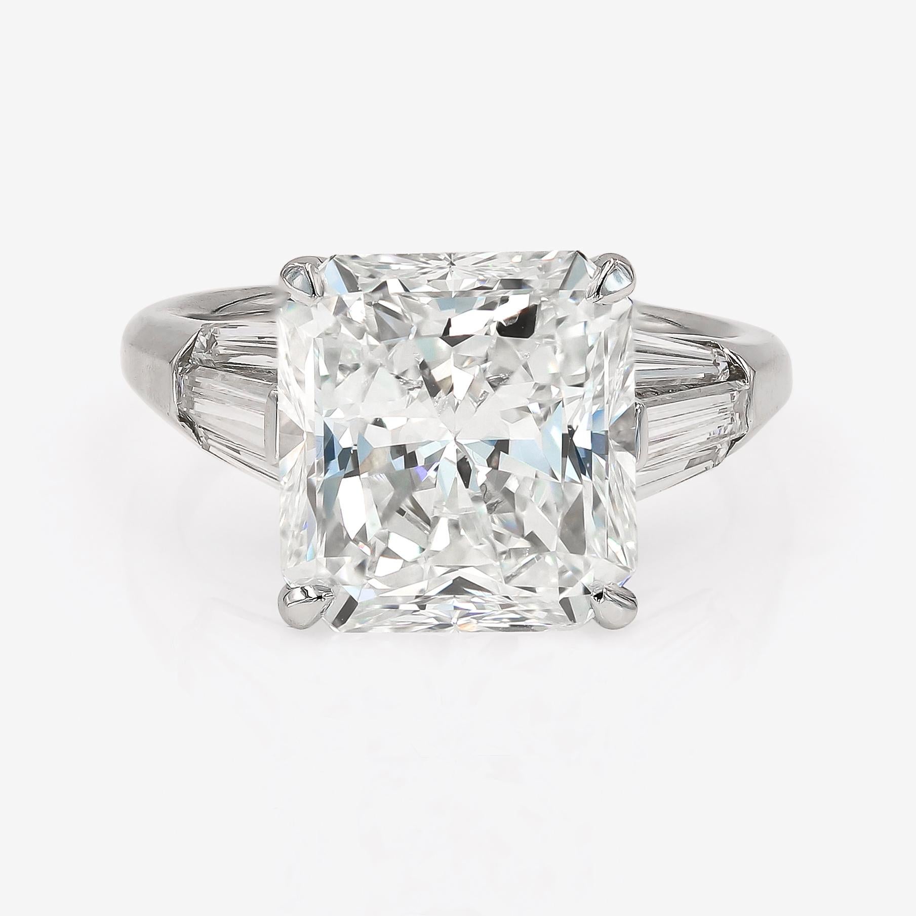 This Lester Lampert original Signature style engagement ring in platinum features a 6.14cts. radiant cut center that is I in color and VS2 in clarity. It is surrounded by 6 long tapered baguette diamonds= 1.13cts. t.w. There are 3 on each side of