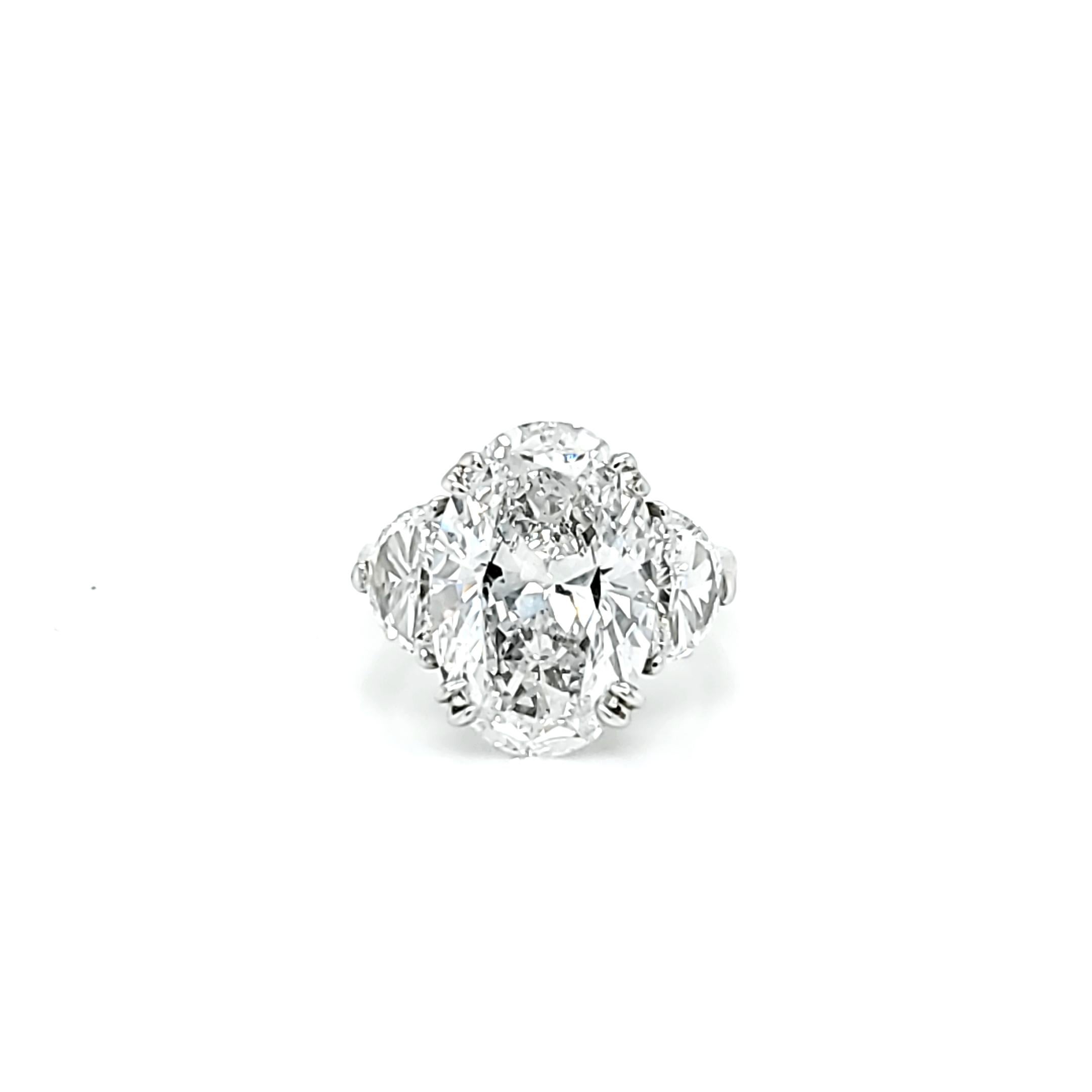Center Stone is 6.16 carat Oval Cut Diamond with a D color and SI2 clarity. Side stones are Half Moon shaped diamonds weighing 1.02 carats total and a similar color and clarity to the center stone. Set in a platinum ring. The Center stone has strong