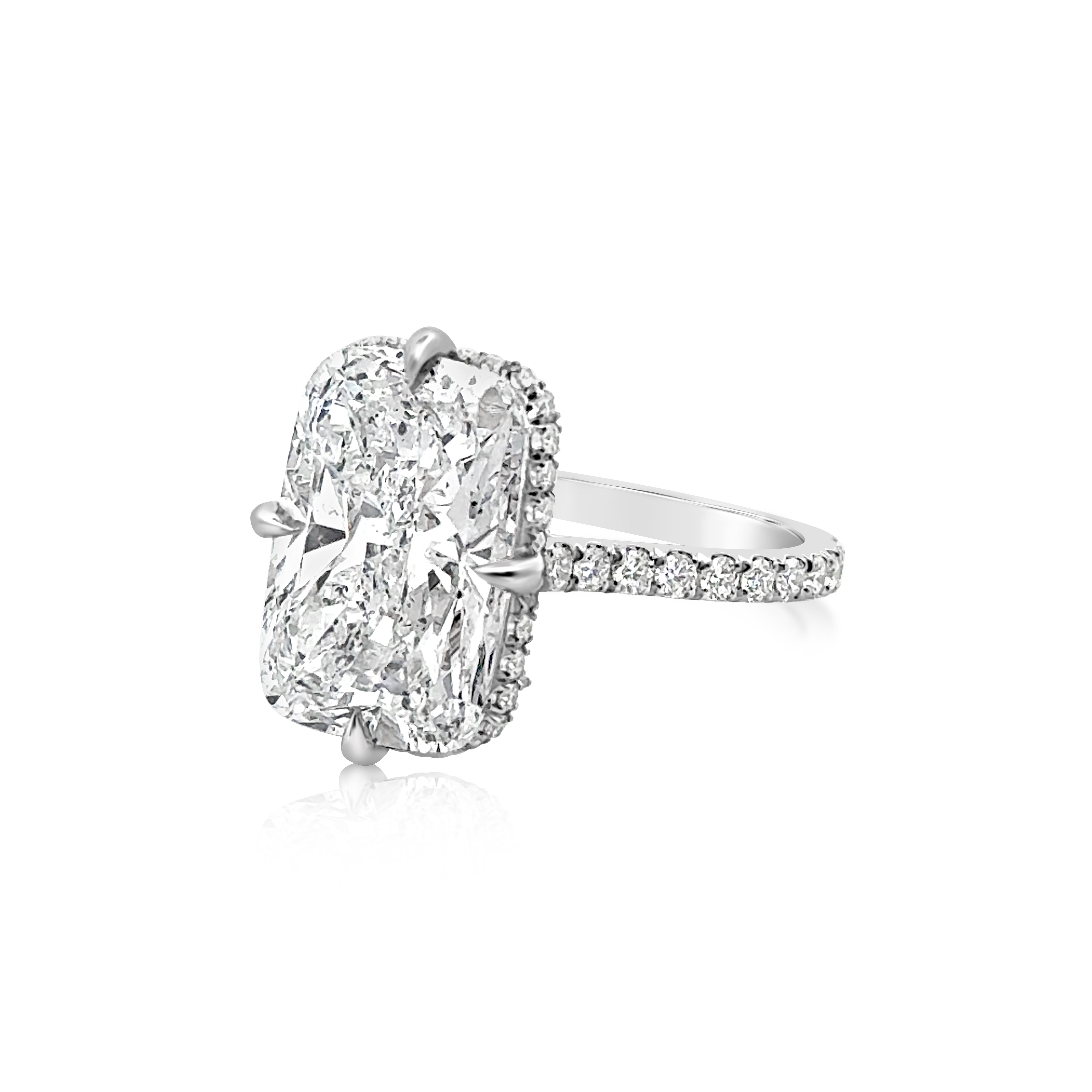 A stunning engagement ring, showcasing a 6.35 carats elongated cushion cut diamond that has a look of an 8+ carat, with D color and SI2 clarity, set on a unique compass prong setting. Accented by round brilliant cut diamonds weighing 0.60 carat