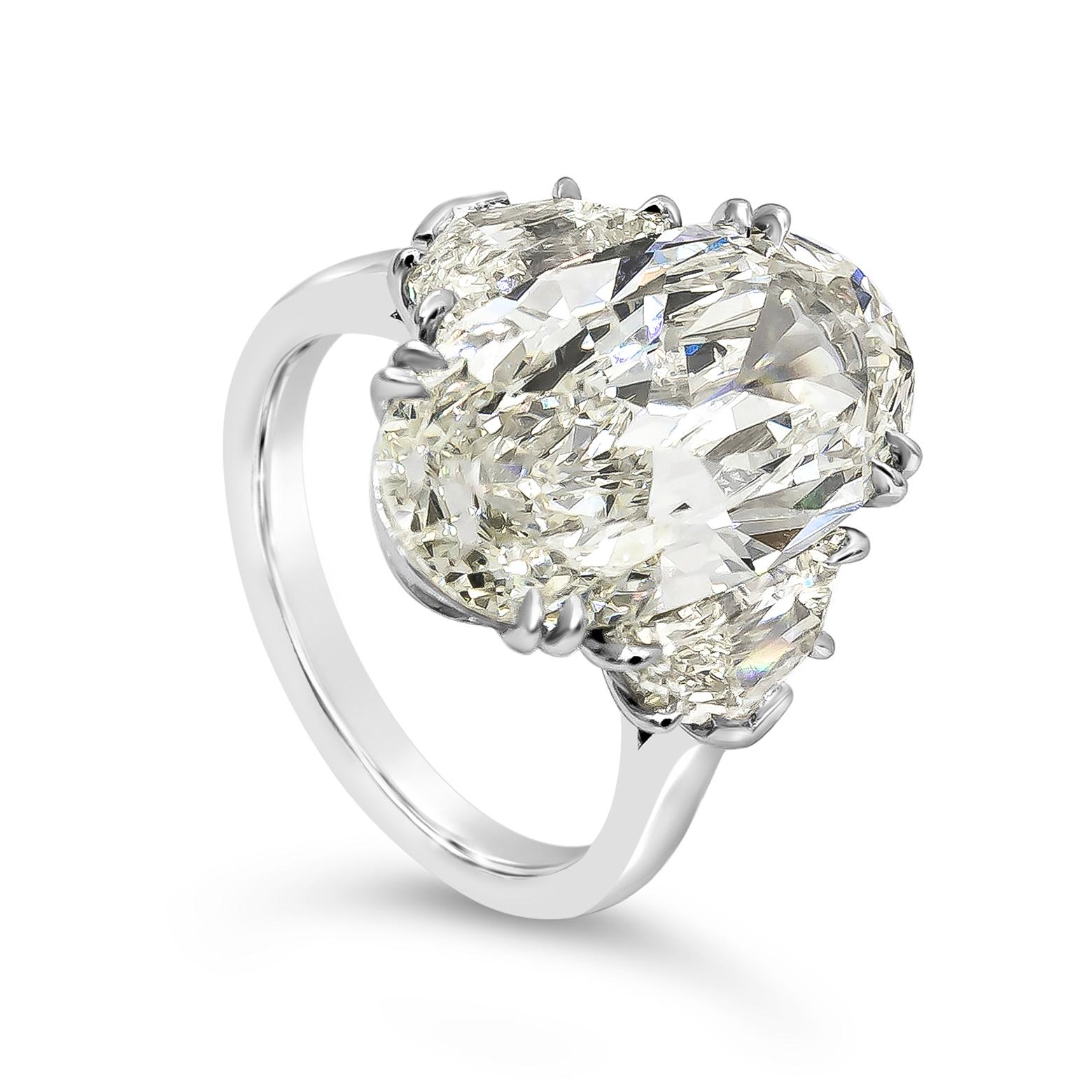An elegant engagement ring, featuring a 6.45 carats elongated oval cut diamond certified by GIA as L color and SI2 clarity, set on an eight prong setting. Flanked by epaulette cut diamonds weighing 1.55 carats total. Finely made with a platinum