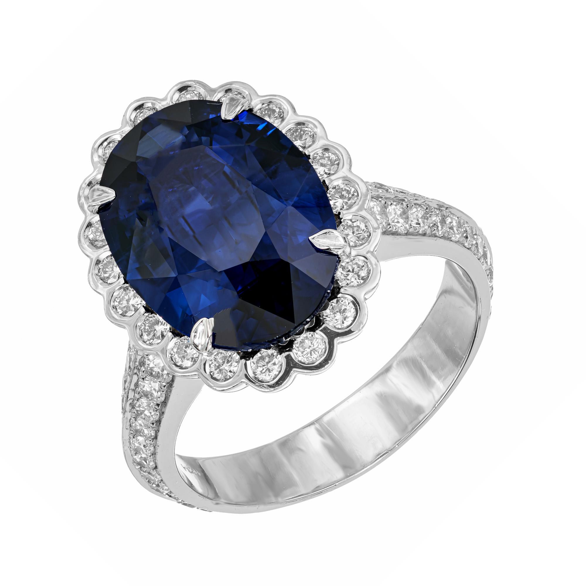 Sapphire and diamond halo engagement ring. GIA certified oval shaped deep blue center sapphire with large surface area, set in a platinum setting with a halo of round bezel set diamonds, accented with two rows of round cut diamonds along both sides