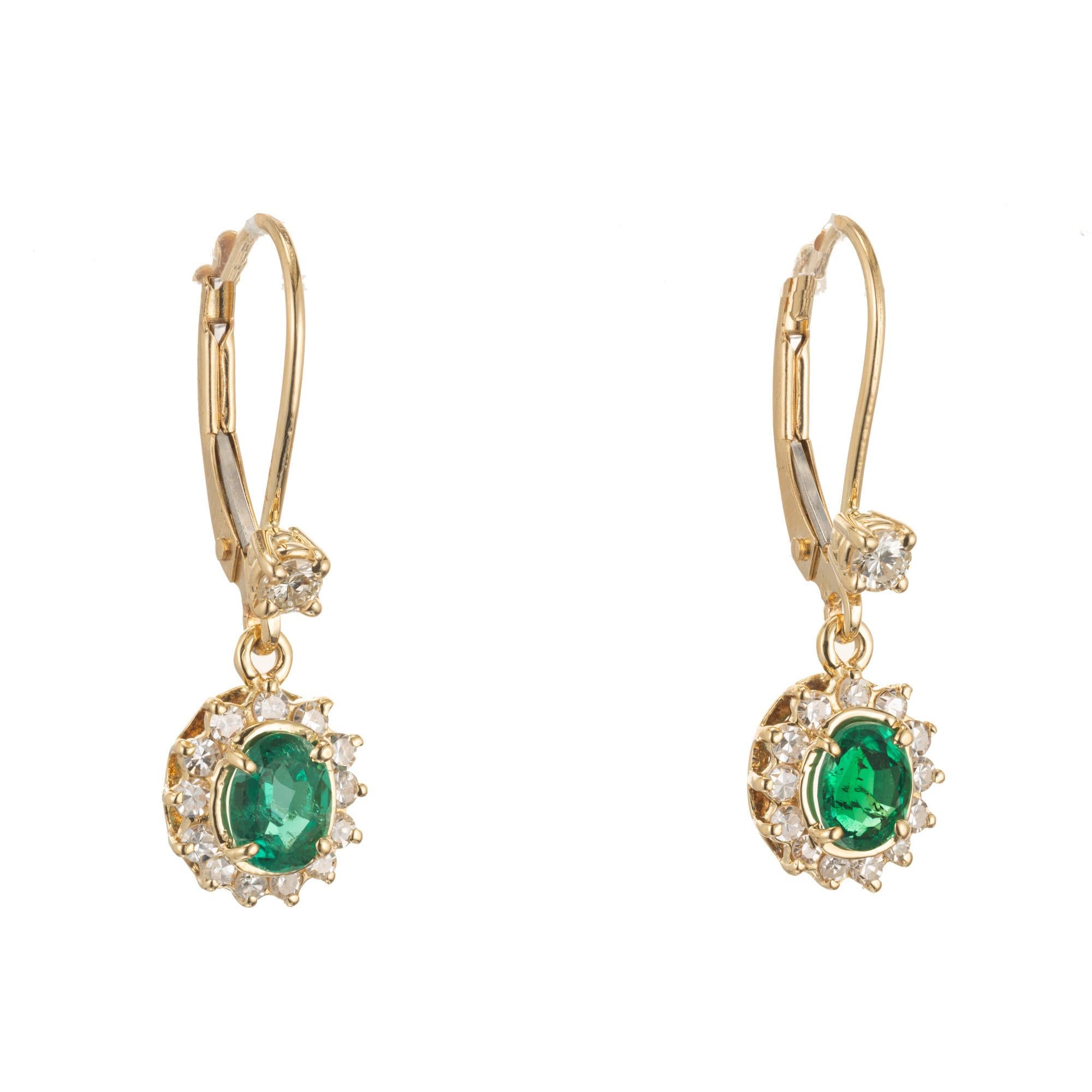 GIA certified oval natural emerald and diamond halo dangle earrings with two round accent diamonds in 14k yellow gold.

2 oval green emeralds, approx. .65cts GIA Certificate # 2201105343
26 single cut diamonds, approx. .32cts H-I VS-SI
2 round