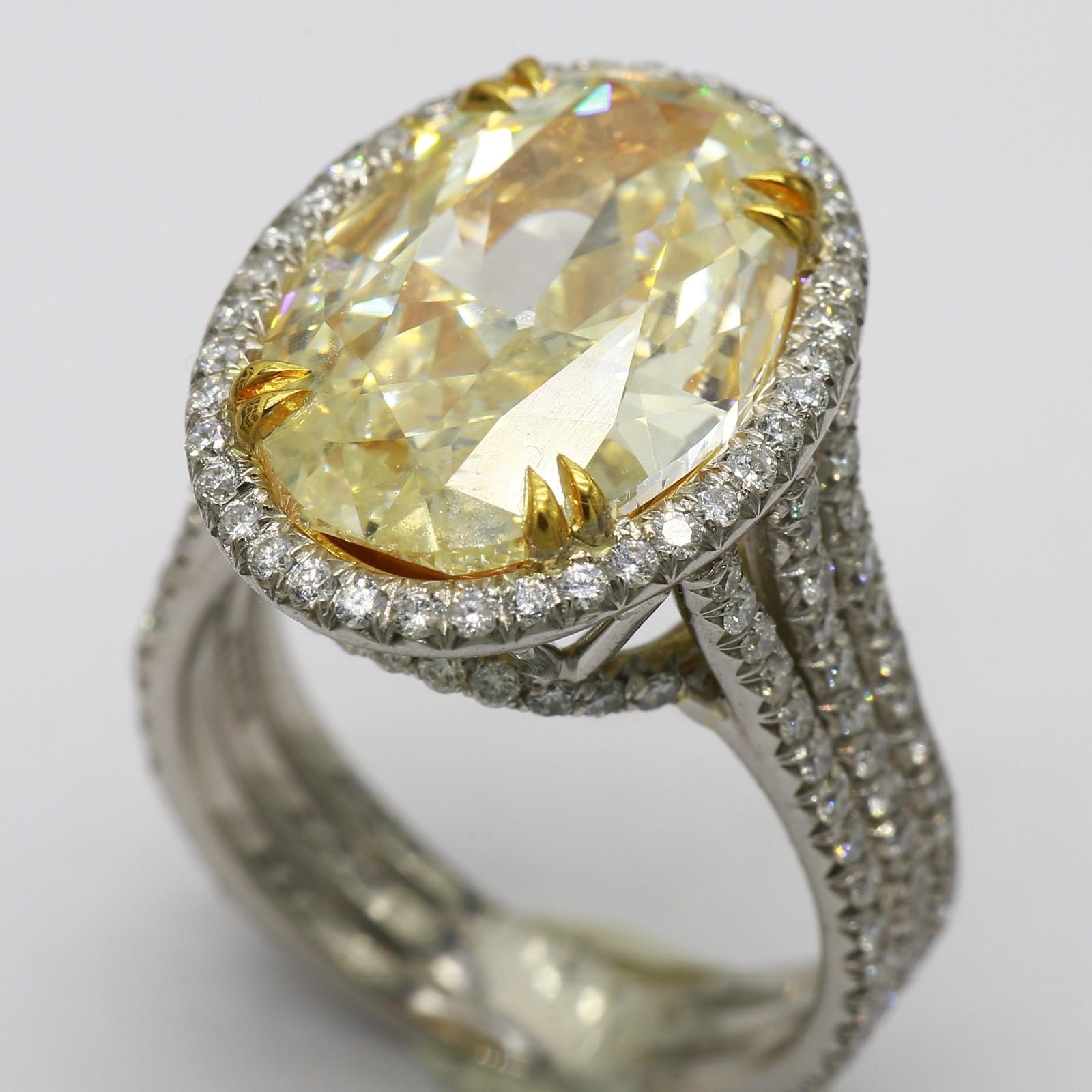 This impressive cocktail ring features a magnificent 6.51 carat natural oval diamond as its centerpiece, color O to P. The substantial size and elegant oval cut make this a truly eye-catching stone. 
The central stone is surrounded by a dazzling