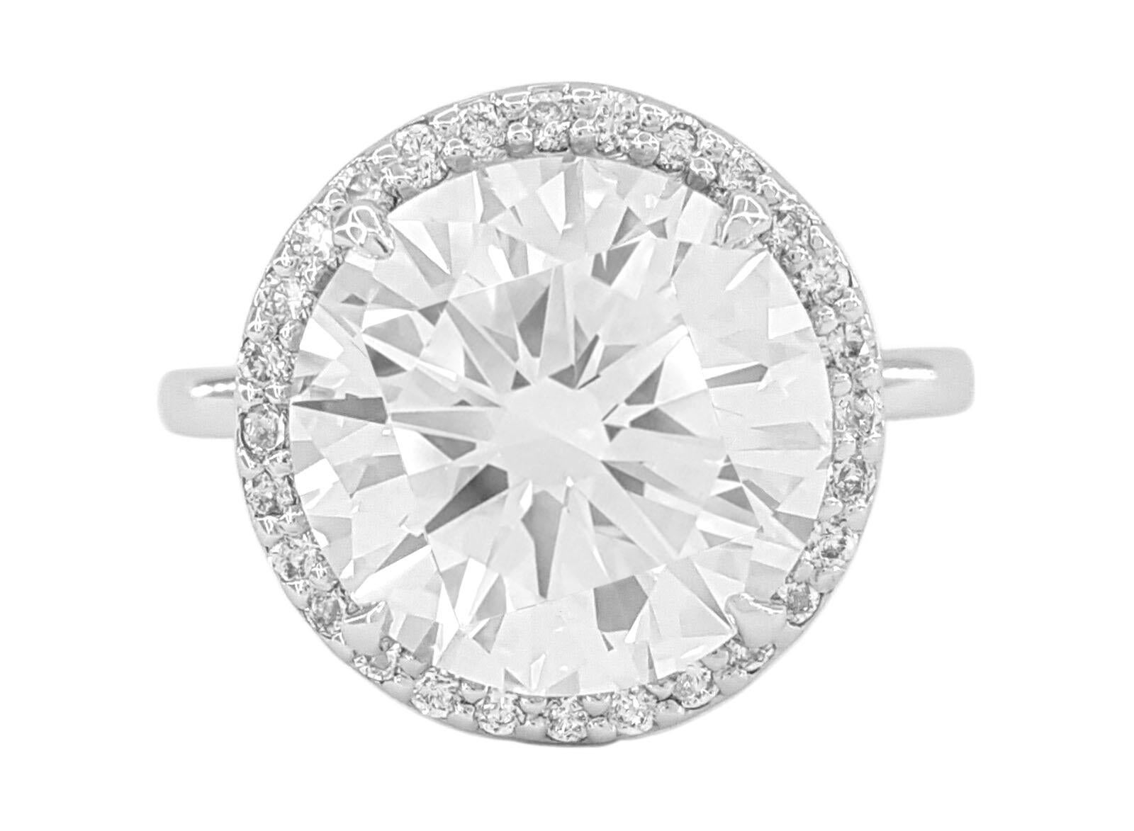 This magnificent 7 carat F color VS clarity round brilliant cut diamond ring set in 18K white gold features an exquisite halo setting, radiating timeless elegance and sophistication. 
At the heart of this exceptional ring dazzles a breathtaking 7