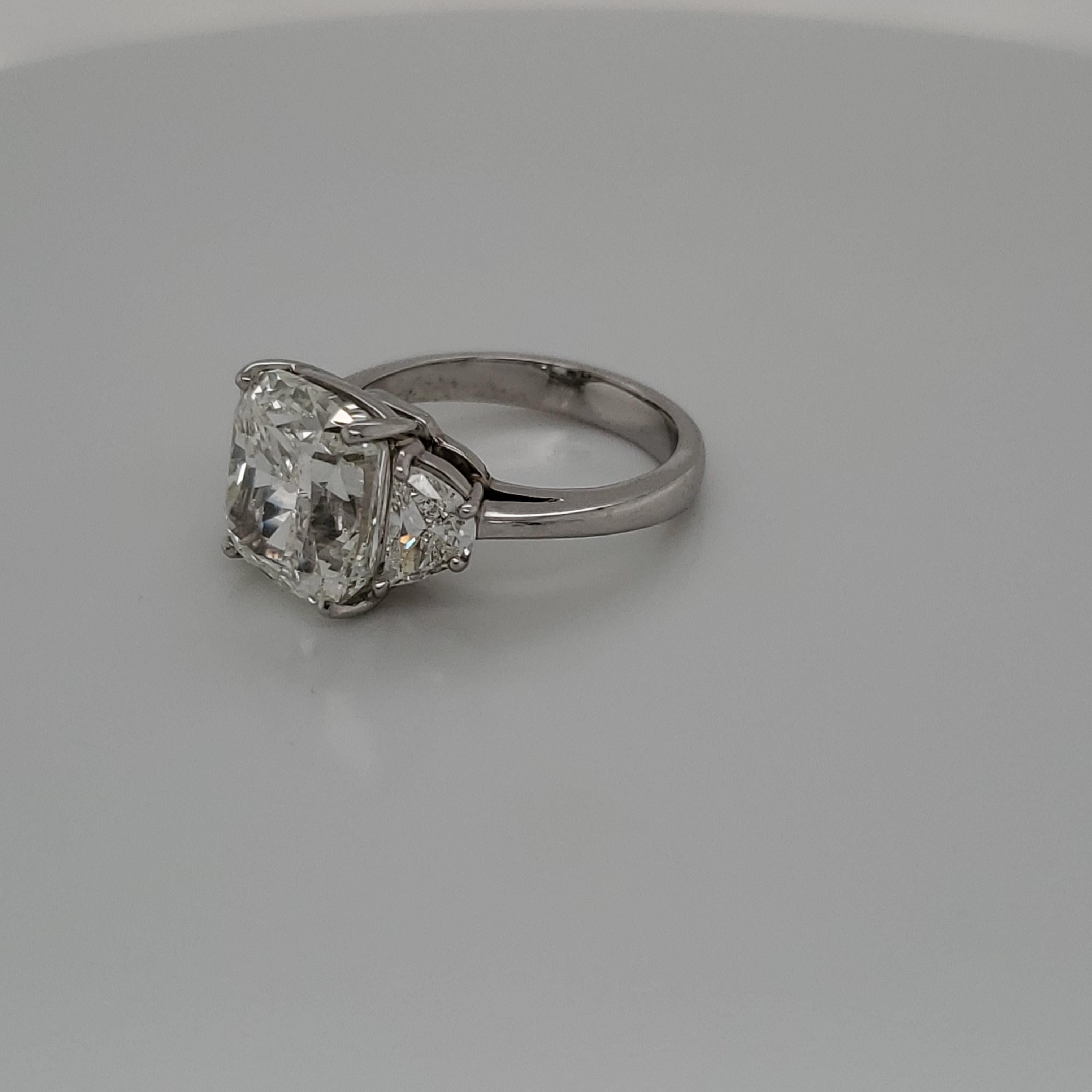 GIA Certified 7.03 carat cushion cut diamond J SI2 set in Platinum with 2 half-moon shaped diamonds weighing 1 carat total. 