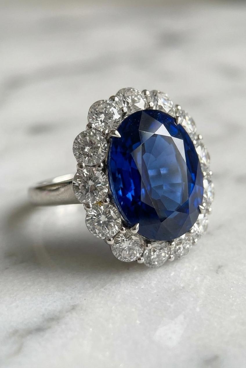 An exquisite cocktail ring showcasing a GIA Certified 7.18 carat natural sapphire of Sri Lankan origin.

The centerpiece is surrounded by 13 natural round brilliant cut diamonds, weighing approximately 2.00 carats in total, graded F color, VS
