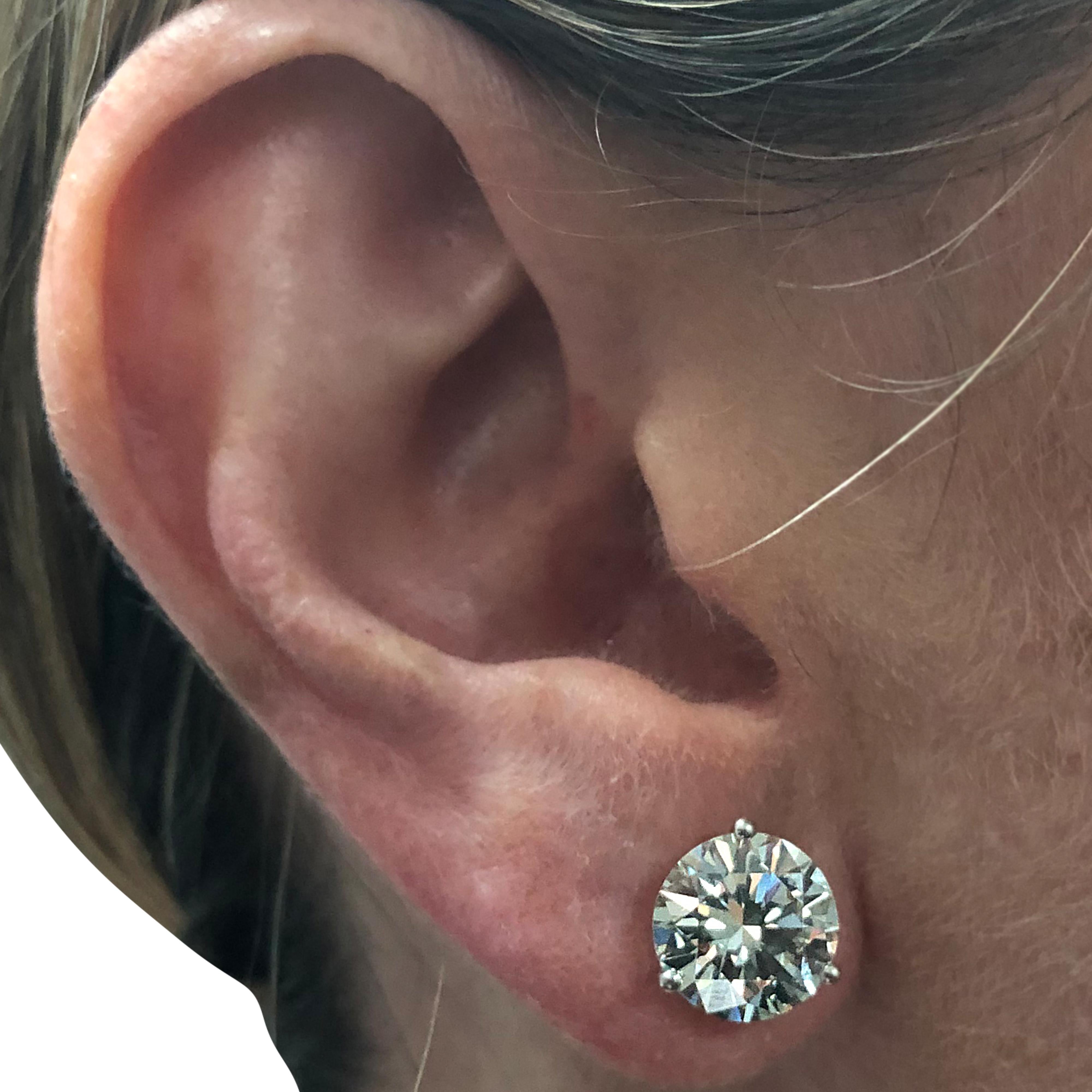 Stunning solitaire stud earrings crafted in white gold, showcasing 2 perfectly matched GIA certified round brilliant cut diamonds weighing 7.19 carats total, M color VS1-2 clarity, with excellent polish and symmetry. These gorgeous earrings are