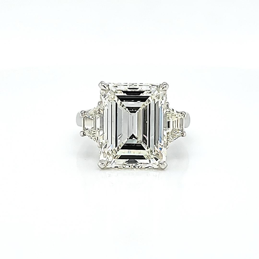 Center stone is GIA certified 7.68 carats K color VVS2 clarity. The trapezoid side diamonds weigh 0.44 carats each and are of matching color and clarity to the center Emerald Cut Diamond. Set in a hand made platinum setting. Currently a size 6.5 but