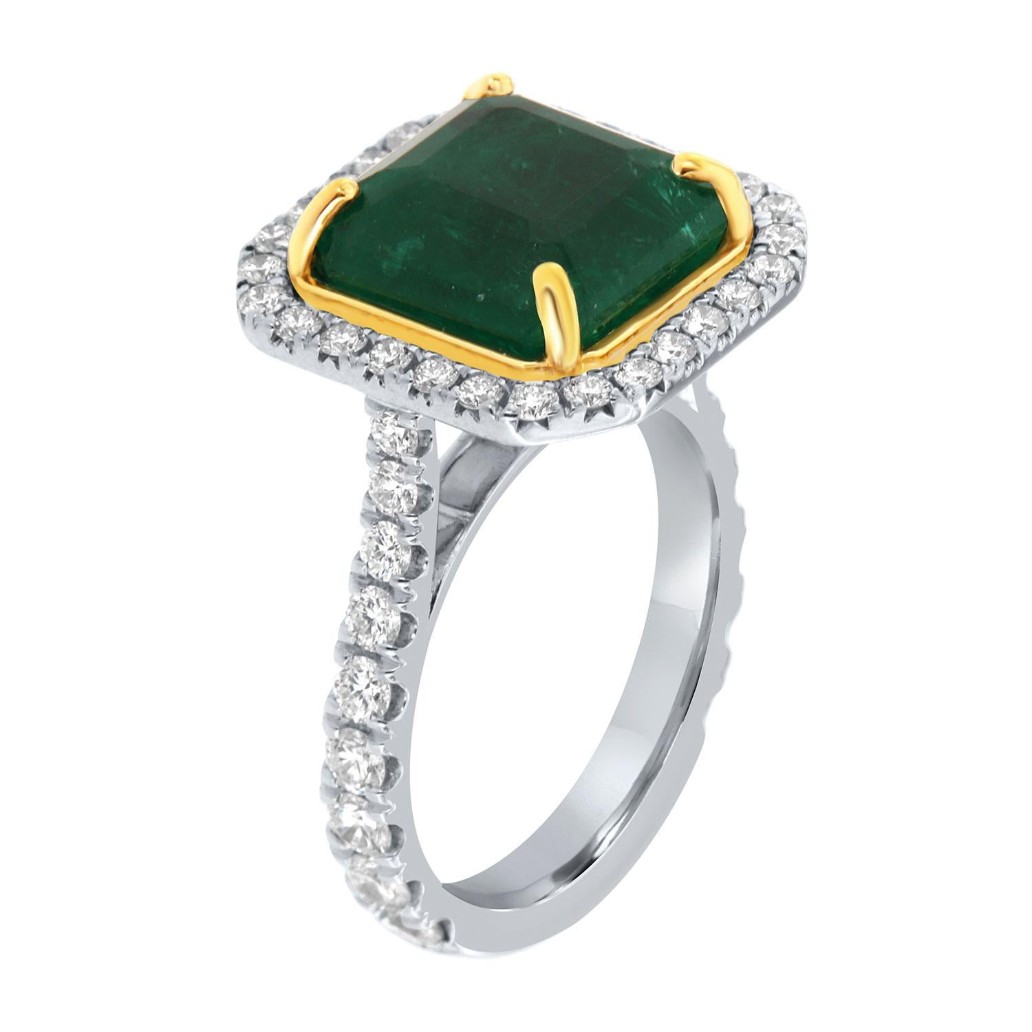 This 18k white and yellow gold ring features a 7.74 Carat Asscher cut Natural Green emerald from Zambia. It is encircled by a halo of brilliant round diamonds on a band that is tapering up starting at 2.4mm wide to 3.4 mm wide. The diamonds are