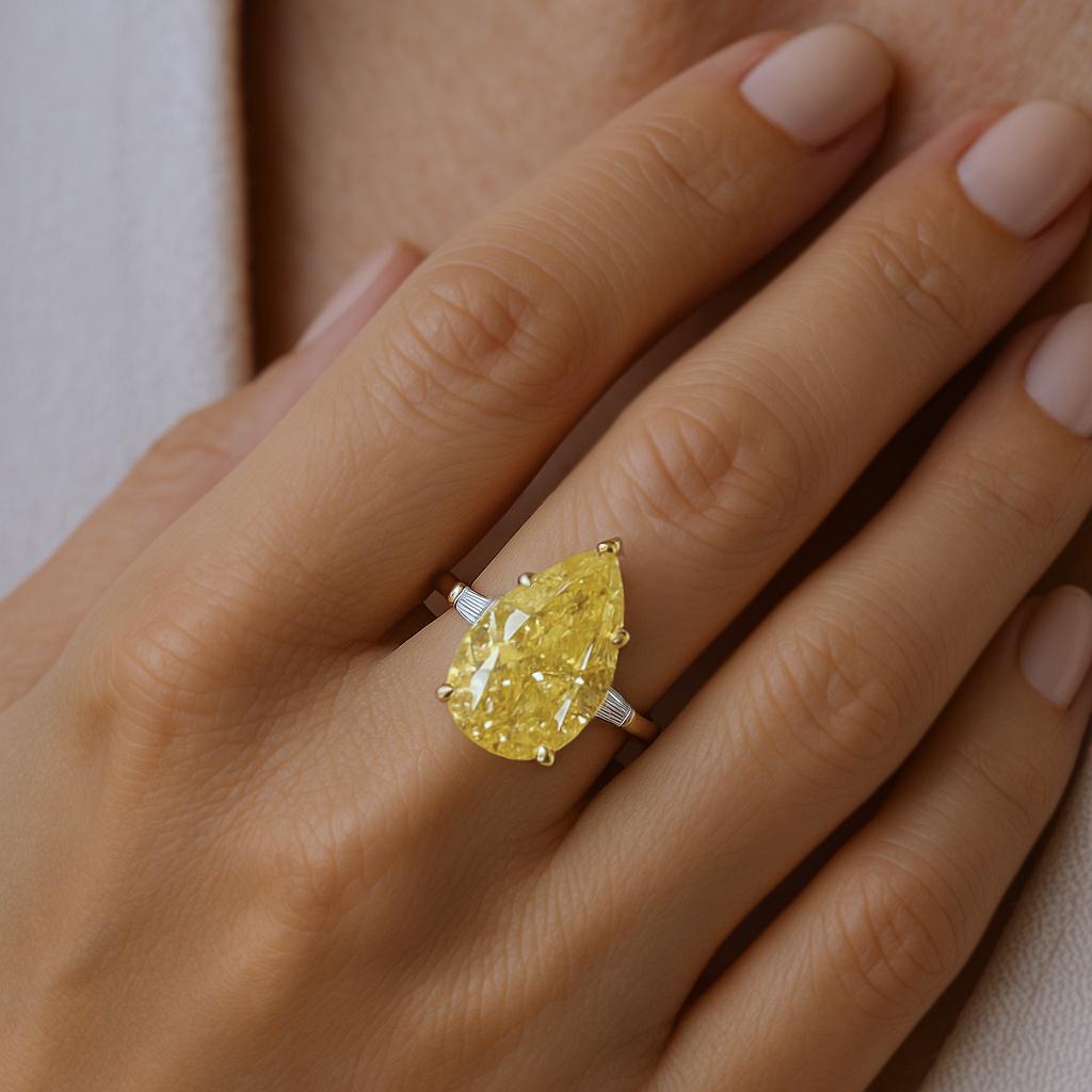 Dieser bemerkenswerte Verlobungsring ist mit einem GIA-zertifizierten gelben Fancy-Diamanten von 7,78 Karat besetzt, der eine leuchtende Farbe und eine außergewöhnliche Präsenz ausstrahlt. 

Das Mittelstück wird durch zwei spitz zulaufende