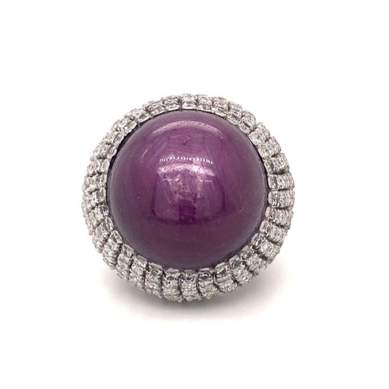 Este grandioso y extraordinario anillo bombe contemporáneo es una poderosa declaración de lujo y elegancia, engastado en oro blanco de 14 quilates. En su corazón yace un impresionante rubí estrella cabujón redondo de 78,67 quilates, certificado por