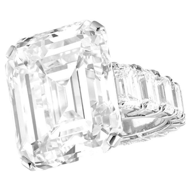 This magnificent engagement ring features a GIA certified 8.03 carat emerald cut diamond set in fine platinum. The centerpiece displays a striking E color grade, offering exceptional icy brilliance with remarkable purity. Its elongated shape and