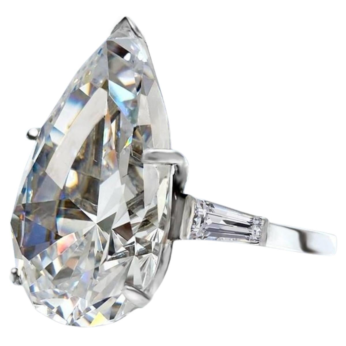 Adorn yourself with the unparalleled elegance of this GIA Certified 8 Carat Pear Cut Diamond Ring, accentuated by tapered baguette diamonds. At the heart of this exquisite ring gleams a stunning pear-cut diamond of extraordinary quality, certified