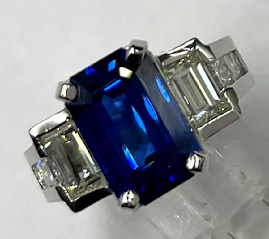 Cette magnifique bague est ornée d'un saphir bleu rare et de grande taille, de 8,12 carats, magnifiquement taillé en émeraude et provenant du Sri Lanka (également connu sous le nom de Ceylan). À côté du saphir se trouvent deux grands diamants blancs