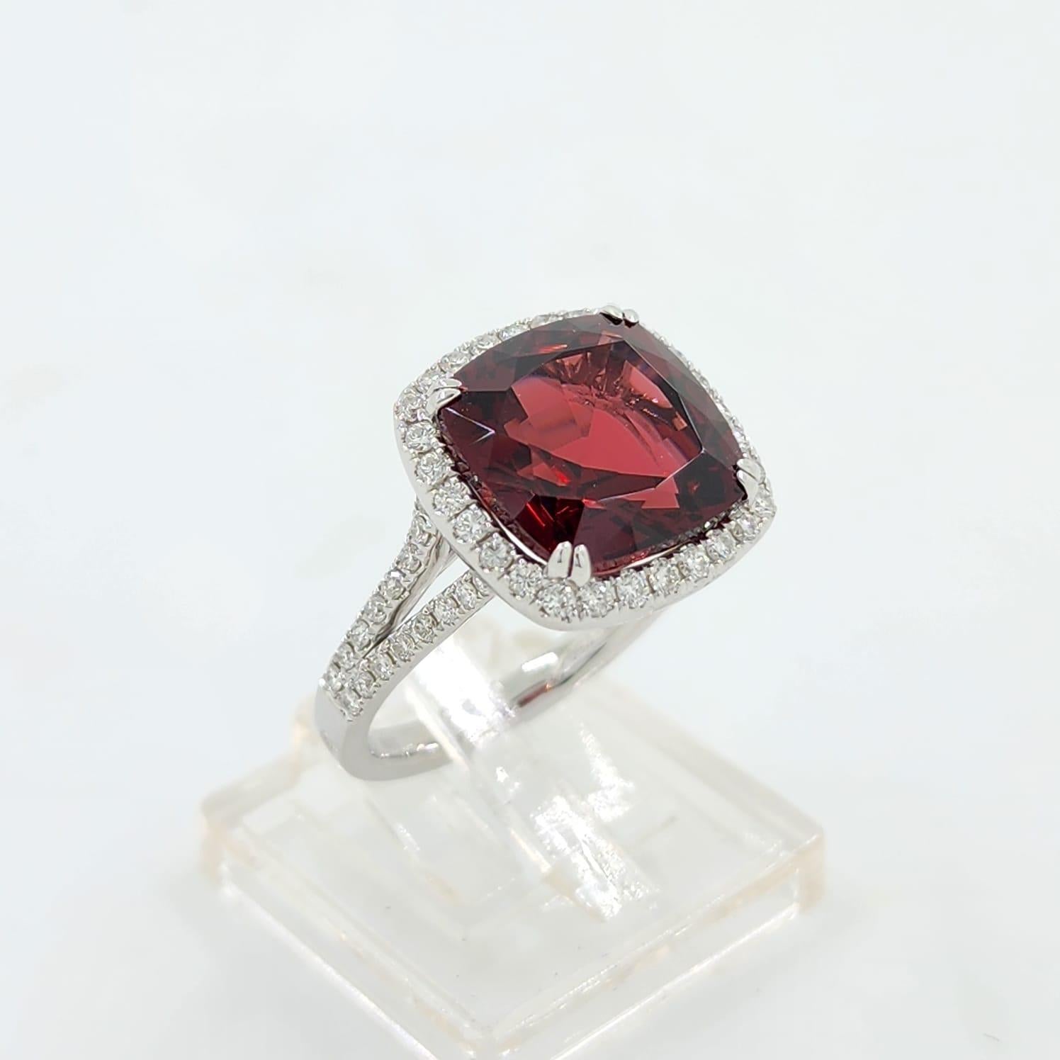 This ring is a striking piece of jewelry, centered upon a GIA certified garnet of 8.15 carats, revered for its deep red color that captures the essence of regality and passion. The garnet is cut into a cushion shape, its facets meticulously crafted