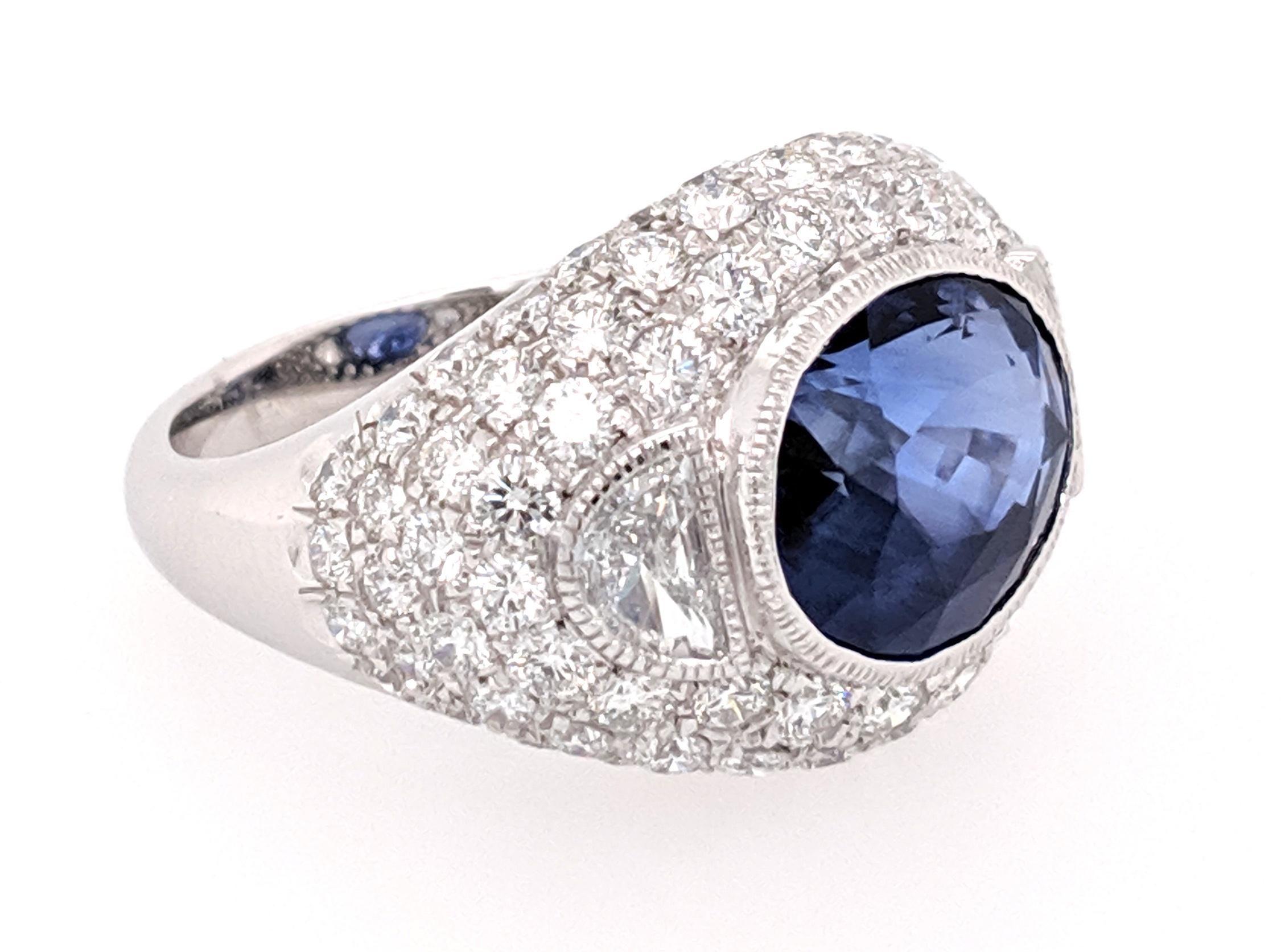 The cocktail ring is crafted in Platinum Featuring (1) Exceptional color oval Sapphire bezel set and weighing 8.23cts and is GIA certified. The sapphire is flanked by (2) half moon shaped diamonds weighing approximately .52cttw and a color of F/G