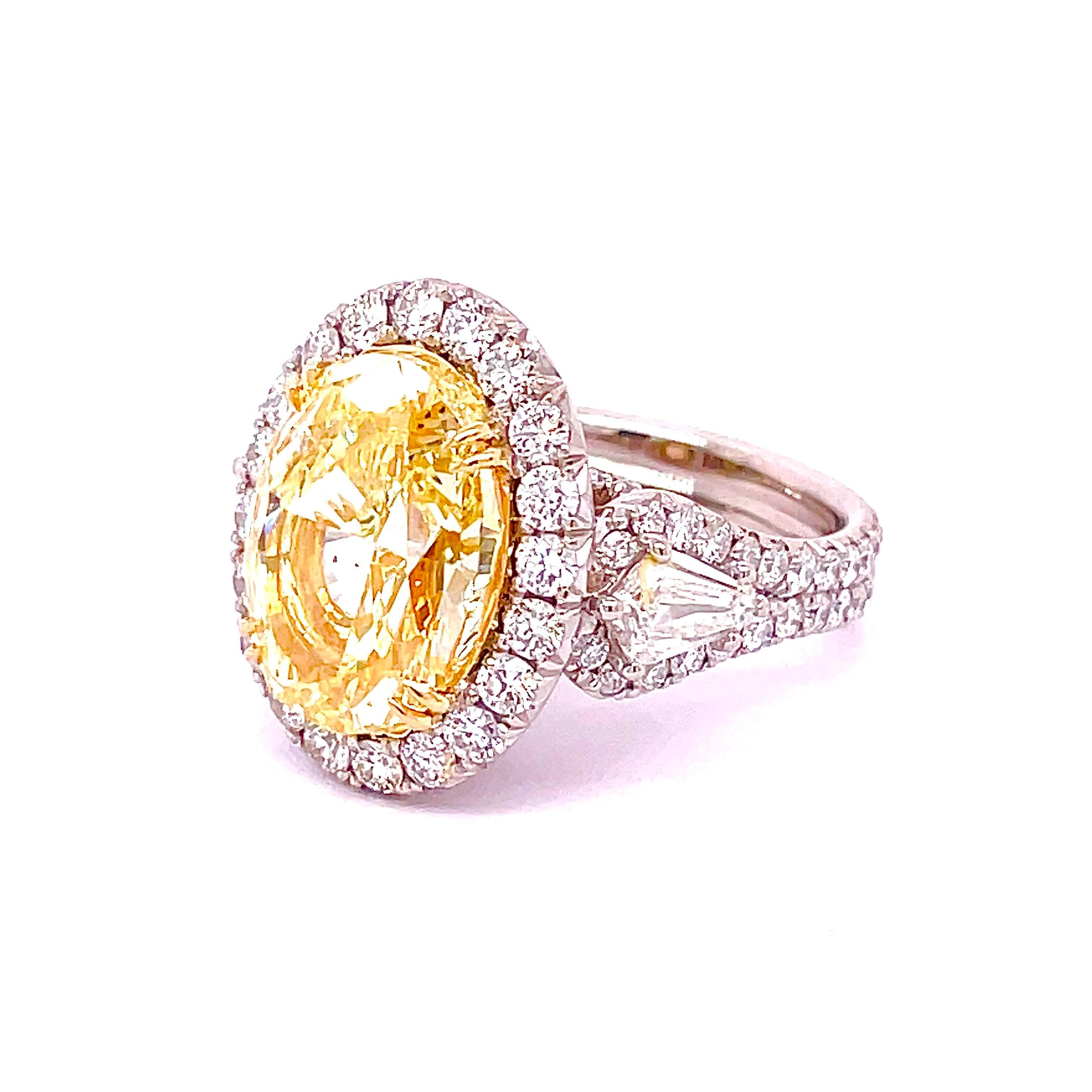 GIA Certified Oval Shape Diamond 8.32, Fancy Yellow Color SI1 Clarity mounted elegantly on a 18K Yellow basket with claw prongs and a Platinum halo & shank filled with 1.93 carat of fine round diamonds. Adding 0.86 carat Shield Cut diamonds on each