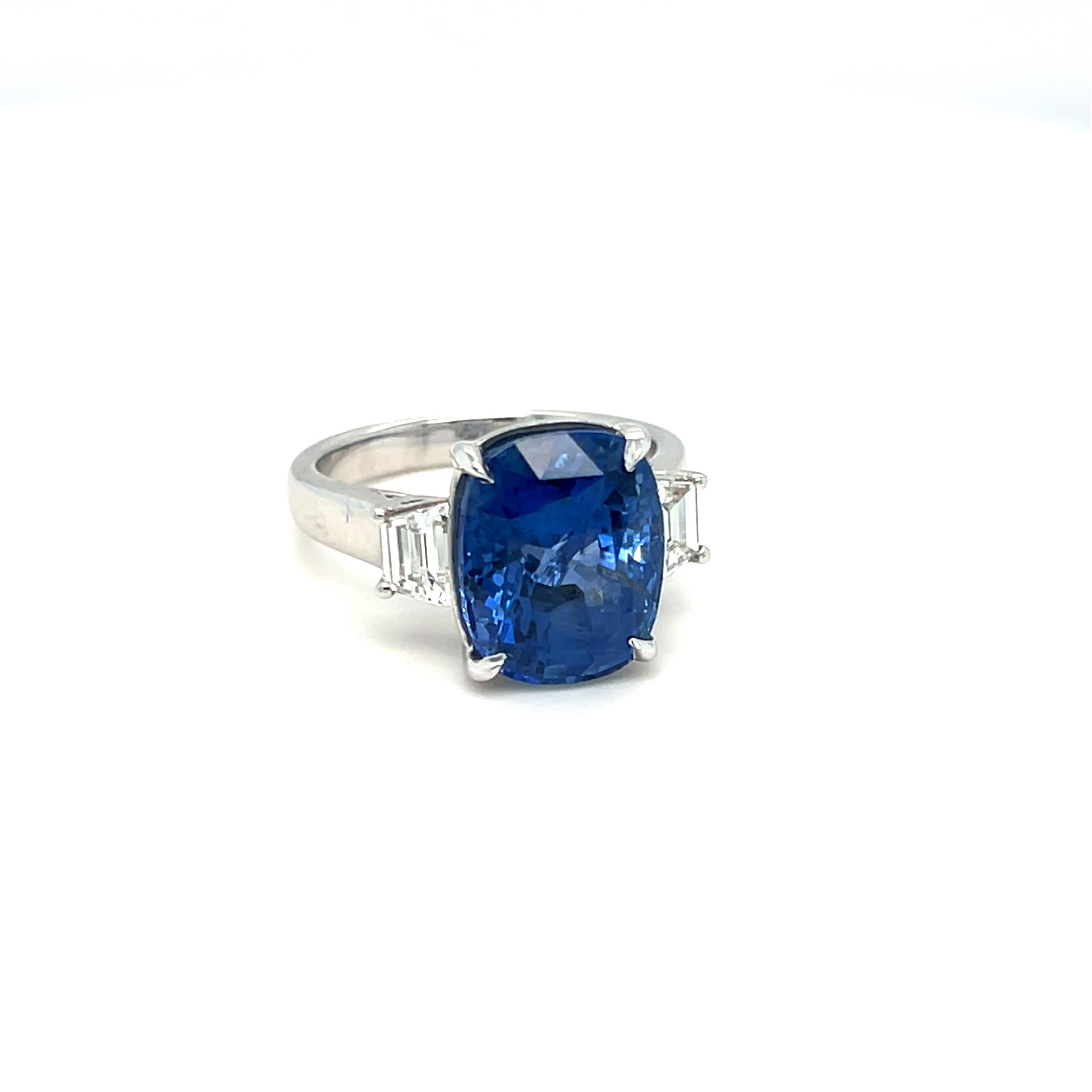 This stunning Gia-certified cushion-cut, no heat blue sapphire ring features a center stone securely set in a four-claw setting, accented by two 0.66-carat trapezoid diamonds positioned east to west. Crafted in 18k white gold, it is a size 7 but can