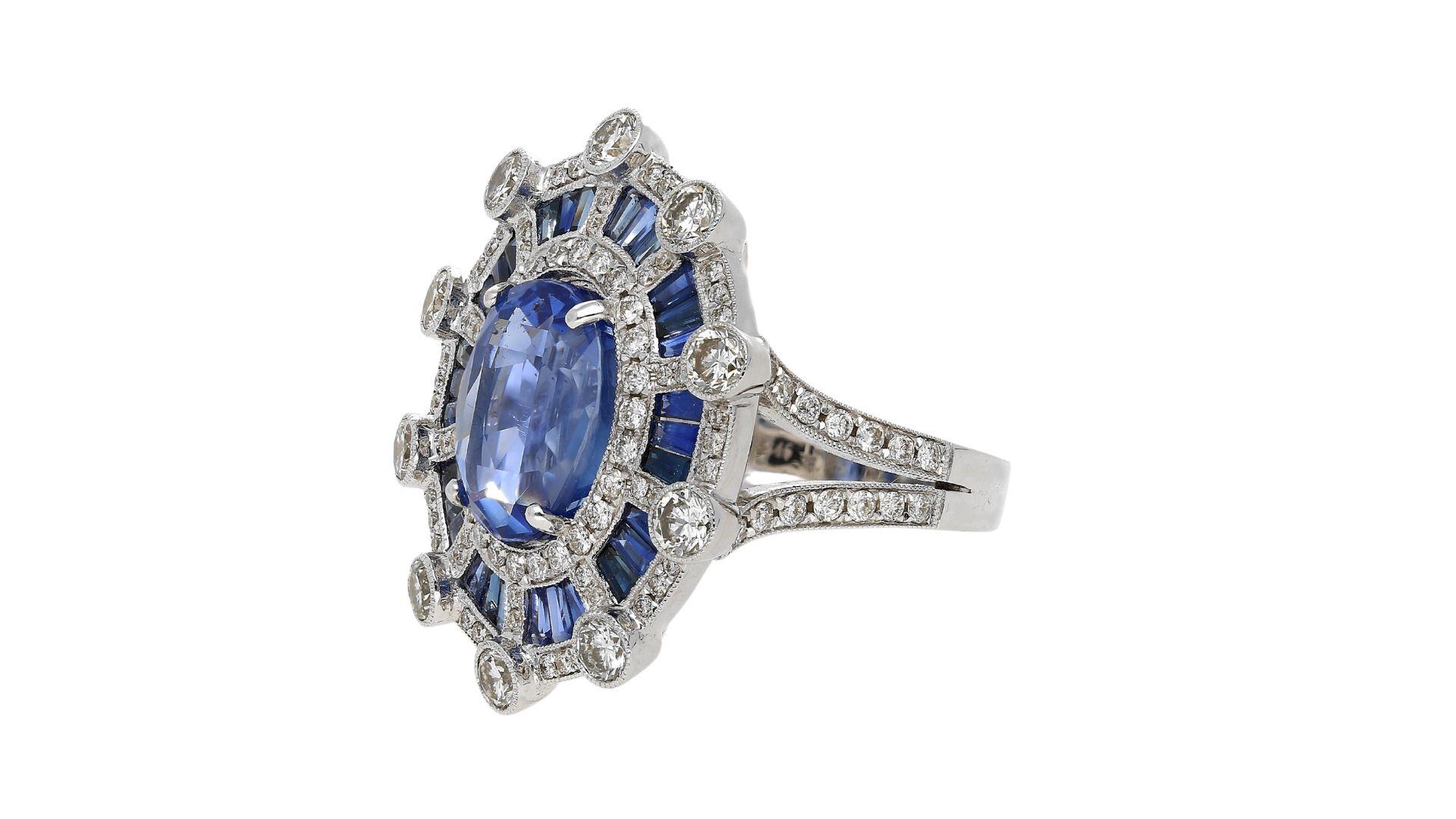 GIA certified 8.46 carat oval cut no heat Sri-Lanka Blue Sapphire & diamond halo ring in geometric art deco style setting. Encompassing the main sapphire are tension set baguette cut sapphires (3.35 cttw), 104 round cut diamonds (0.95 cttw), and 10