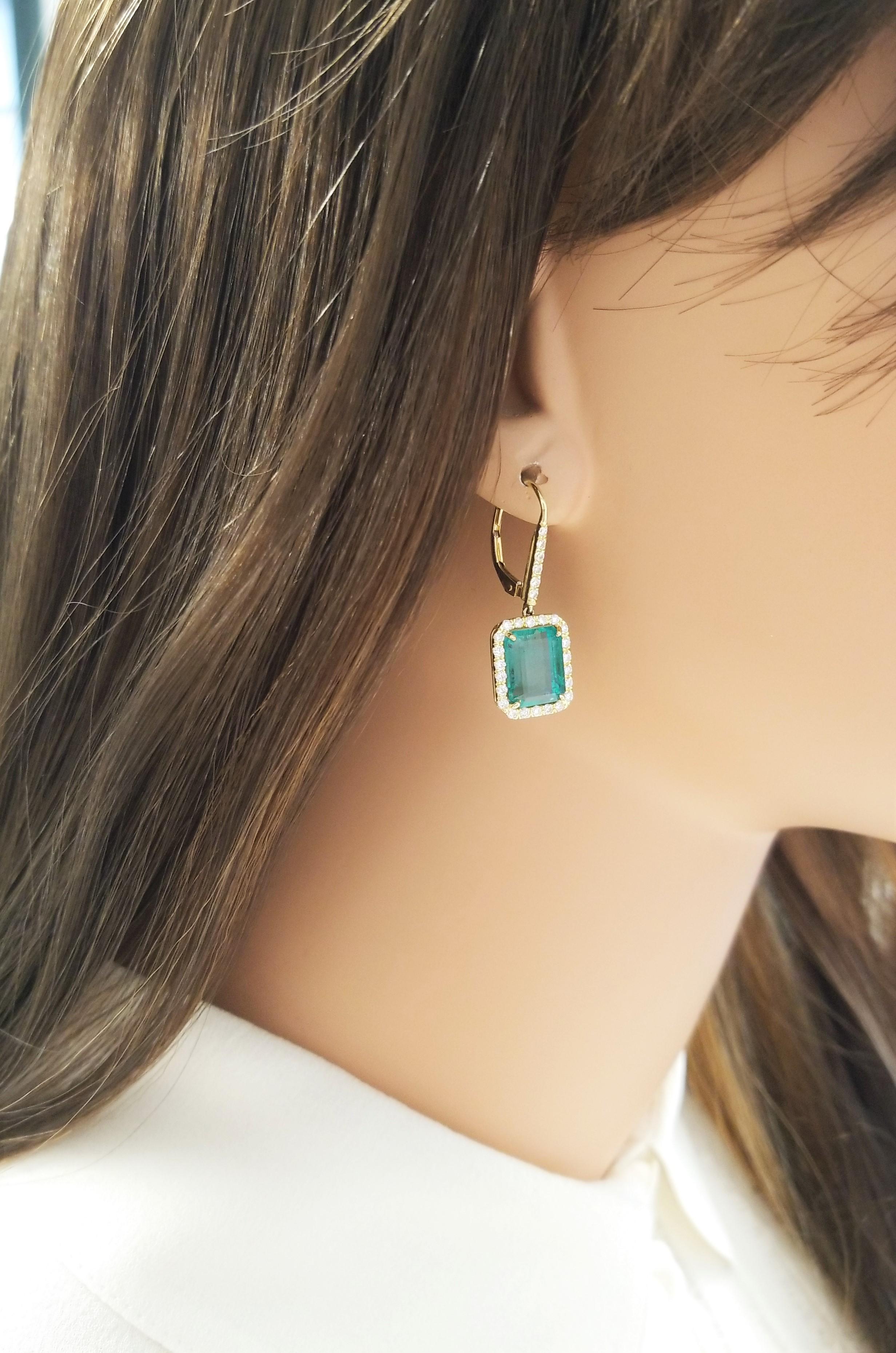 These dangle earrings feature two GIA certified emerald cut green emeralds, prong set in lavish drops, totaling 8.55 carats and measuring 10.24-8.23mm each. The gem source is Brazil; they are perfectly matched in size, color, transparency, and