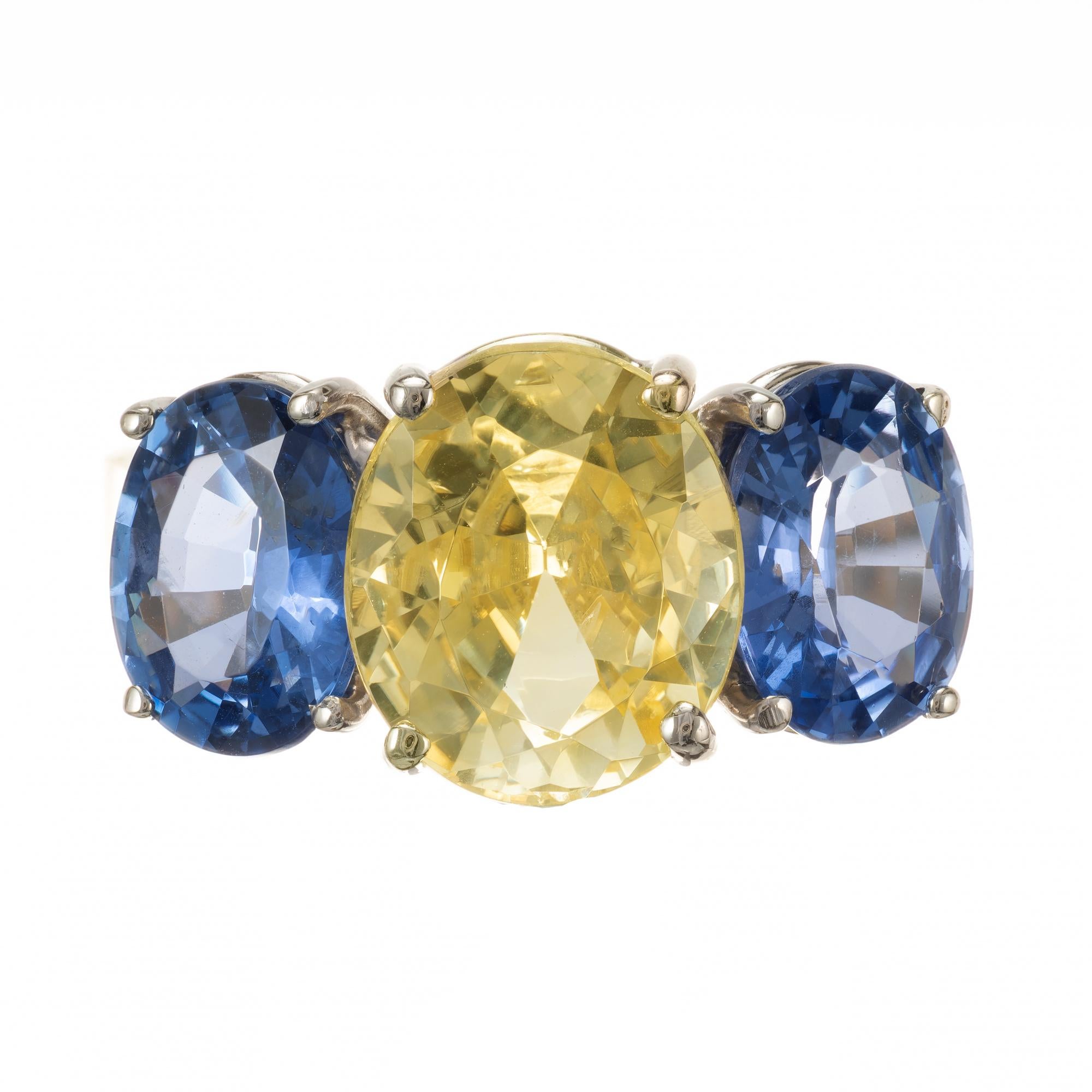 Oval Natural light lemon yellow Sapphire and blue sapphire three-stone engagement ring. The center stone is GIA certified with GIA certified blue sapphires on each side. Set in 18k yellow gold setting. 

1 oval natural fine bright soft lemon yellow