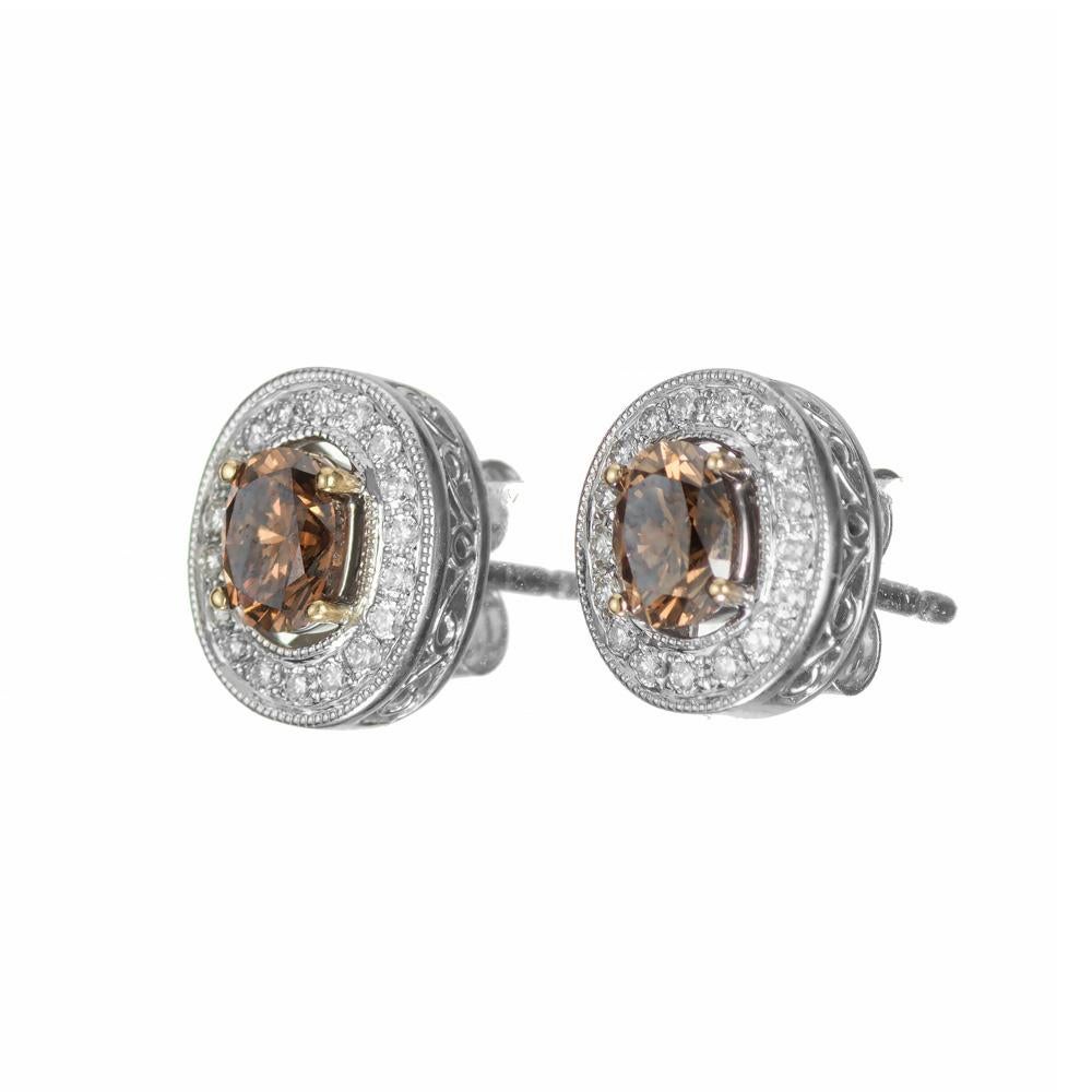 Bright orangy brown GIA certified natural diamonds. Very well matched. Oval halo style setting with diamonds in 14k whtie gold.

1 oval fancy dark orangy brown diamond, SI approx. .46cts GIA Certificate # 22225490621
1 oval fancy orange brown