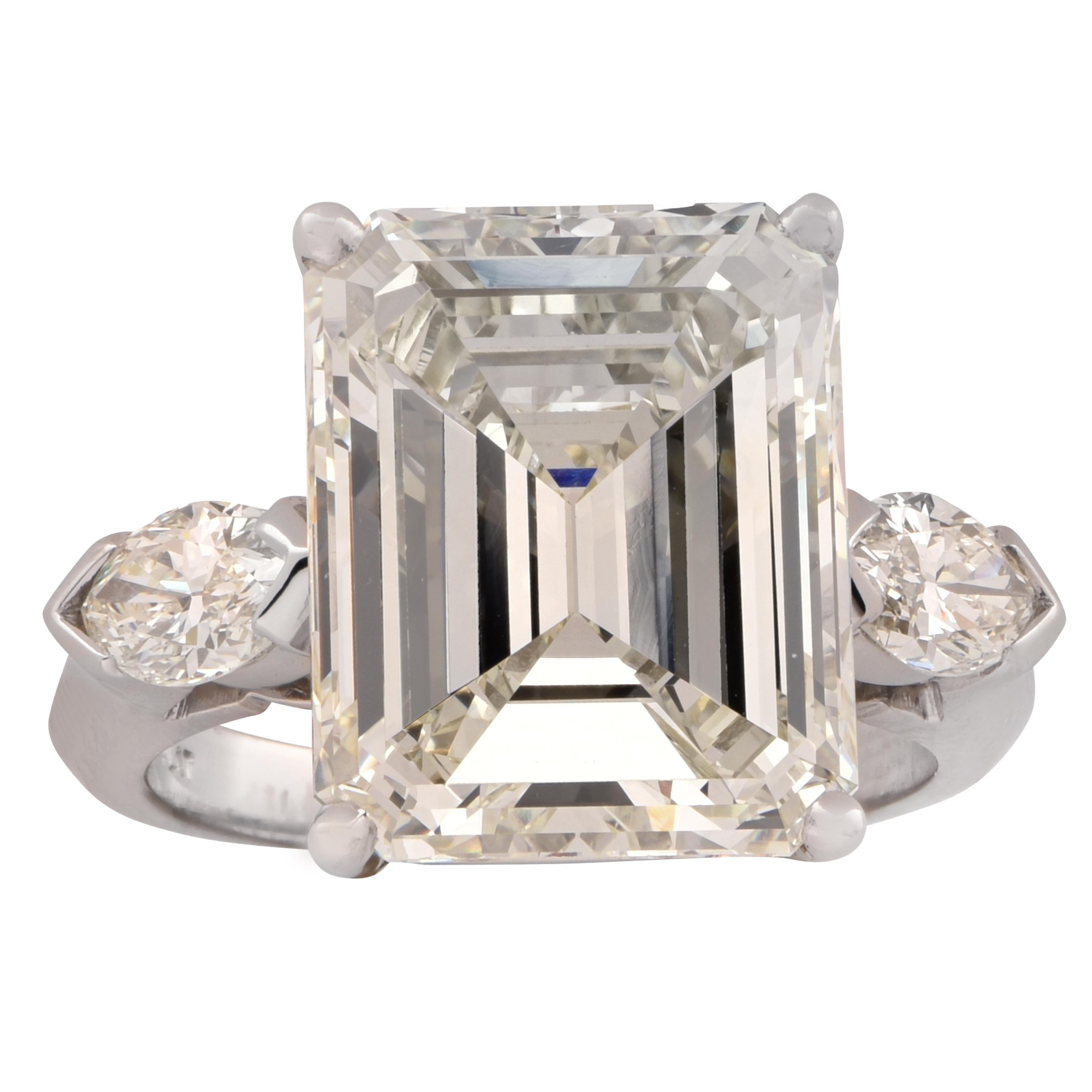 Spectacular engagement ring crafted in platinum showcasing a stunning GIA certified Emerald Cut Diamond weighing an impressive 9.29 carats, L color, VVS2 clarity. The band of the ring is adorned with 2 marquise cut diamonds weighing .60 carats
