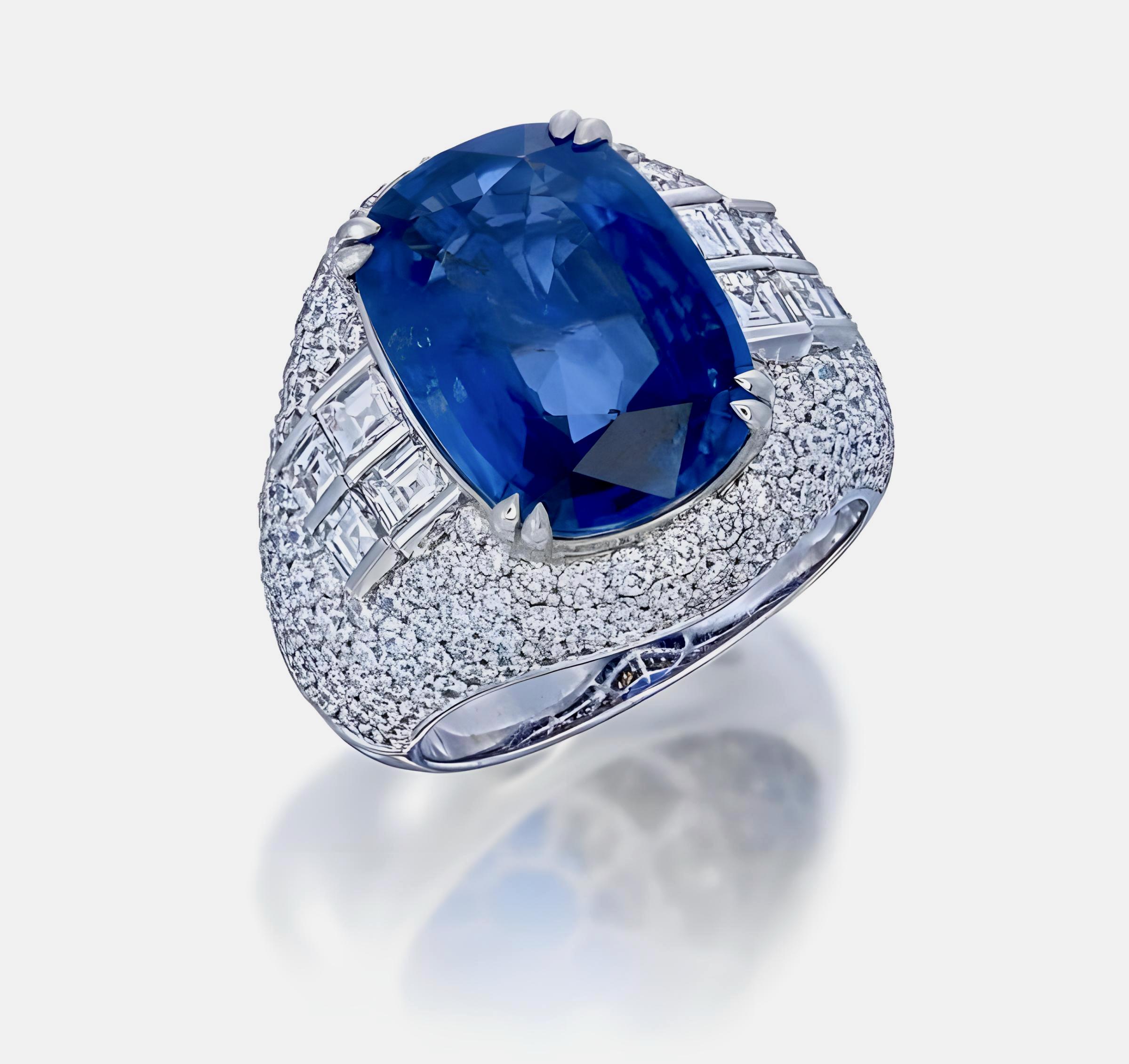 This ring showcases a 9.49-carat GIA-certified Sri Lanka heated blue sapphire in a classic cushion cut (certificate number GIA6501222681). Surrounding the sapphire are 2.63 carats of round-cut diamonds and 0.91 carats of carré-cut diamonds, creating