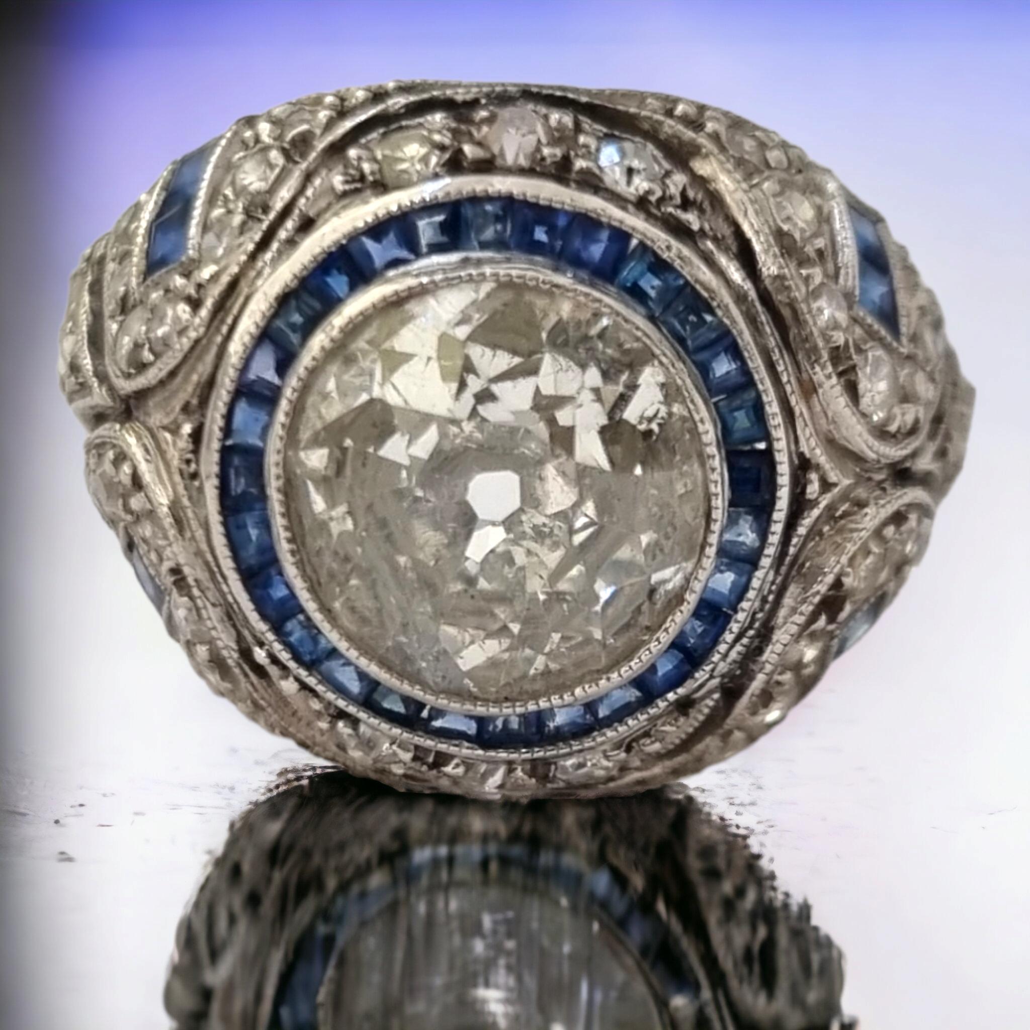 GIA-zertifizierter antiker Art-Deco Diamant und blauer Saphir Ring in Platin gefasst
Art Deco Verlobungsring, brutzelt in der Mitte mit einem hell-weißen und funkelnden Diamanten im europäischen Schliff mit einem Gewicht von ca. 2,05 bis 2,10 Karat