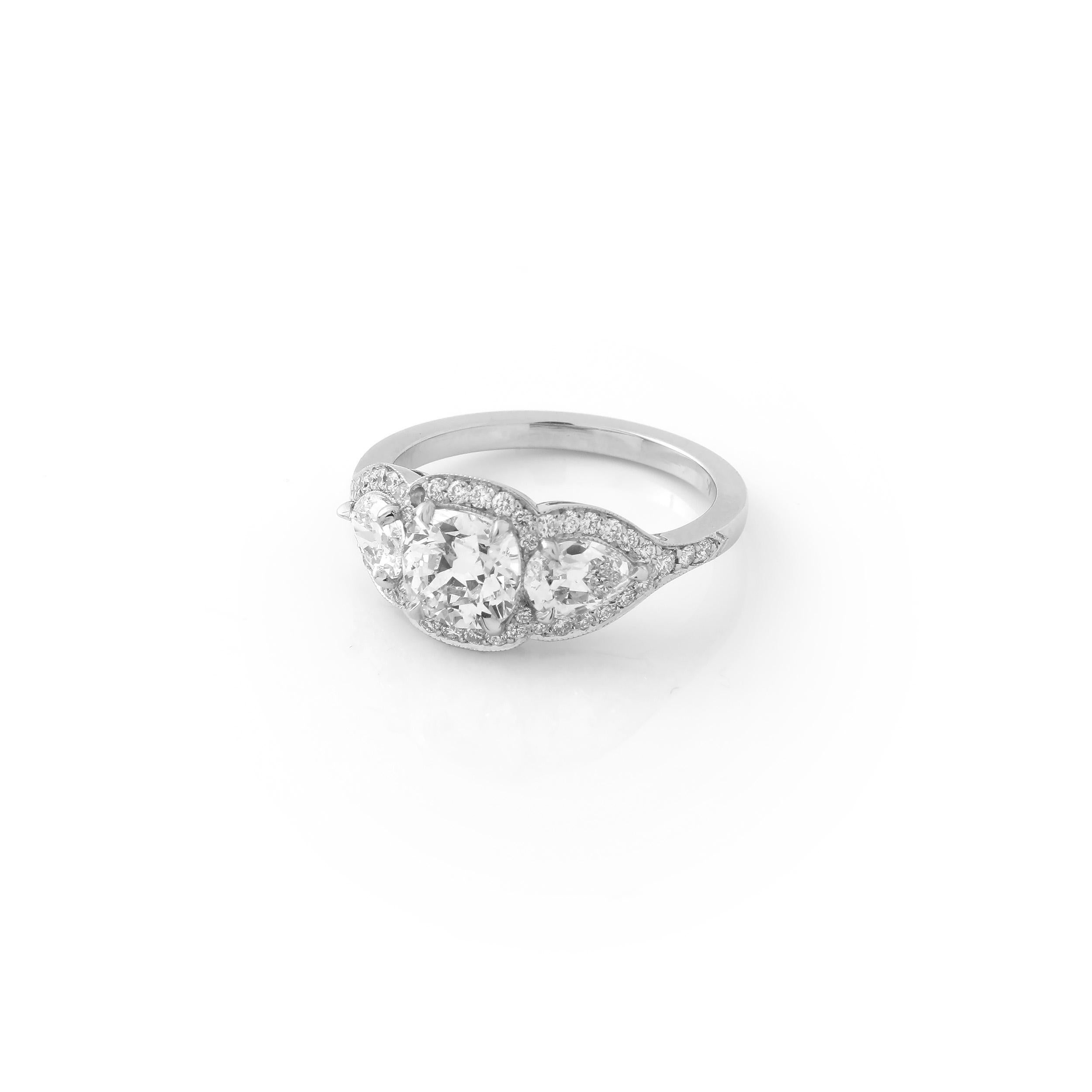 This three-stone ring features a GIA certified 1.01 carat F VS1 antique-cut cushion center and a pair of F/G VS antique-cut pear shape side stones, weighing 0.86 carats. The three diamonds are set in a beautiful pavé platinum mounting giving the