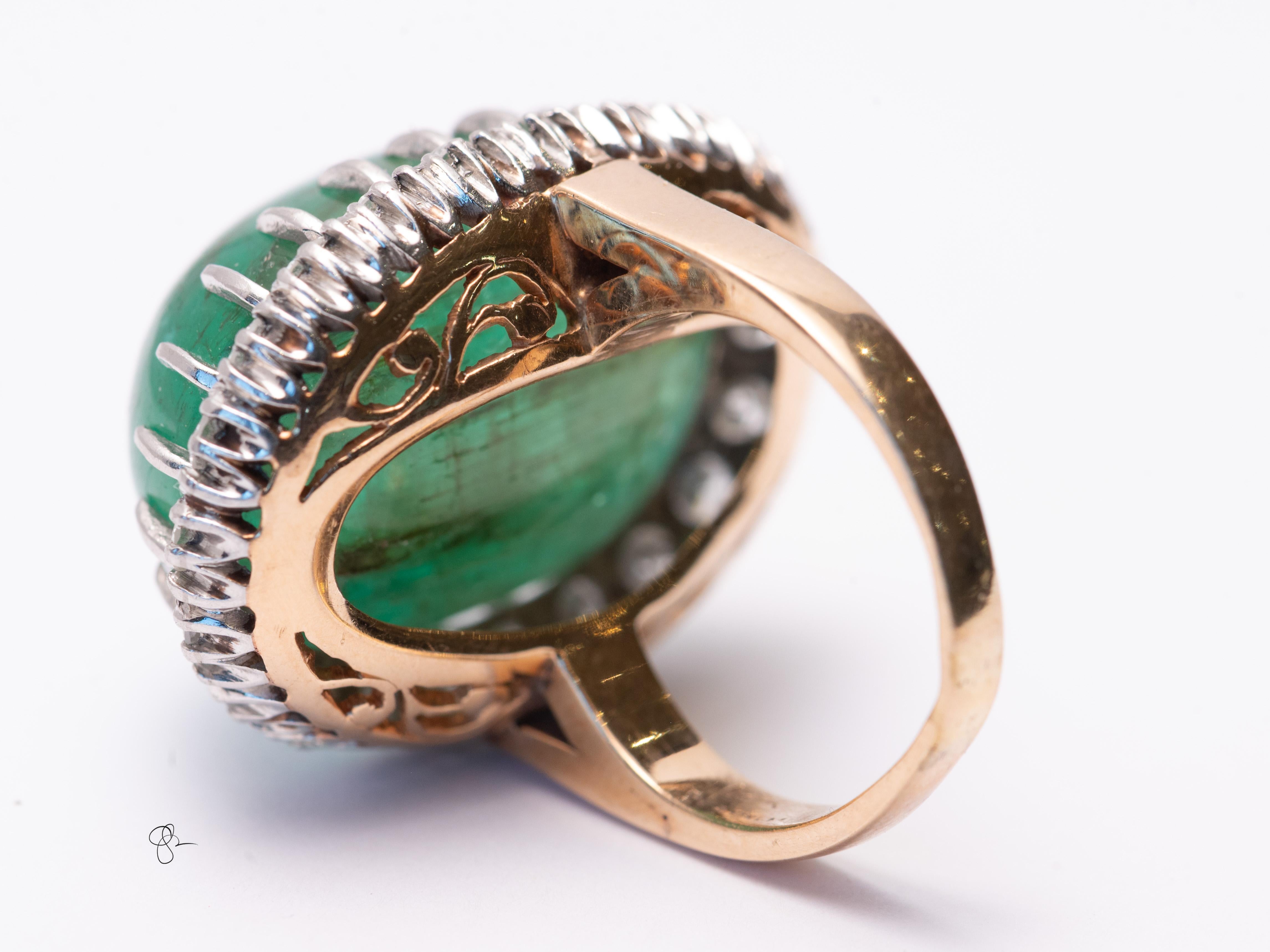 Gefertigt aus 14k Gelbgold wiegt das Stück 20,9 Gramm. Der Diamant-Halo besteht aus zweiundzwanzig 3 mm großen runden Diamanten von schätzungsweise 2 Karat. 
Wir präsentieren einen auffälligen Ring mit Cabochon-Smaragd und Diamanten, der durch den