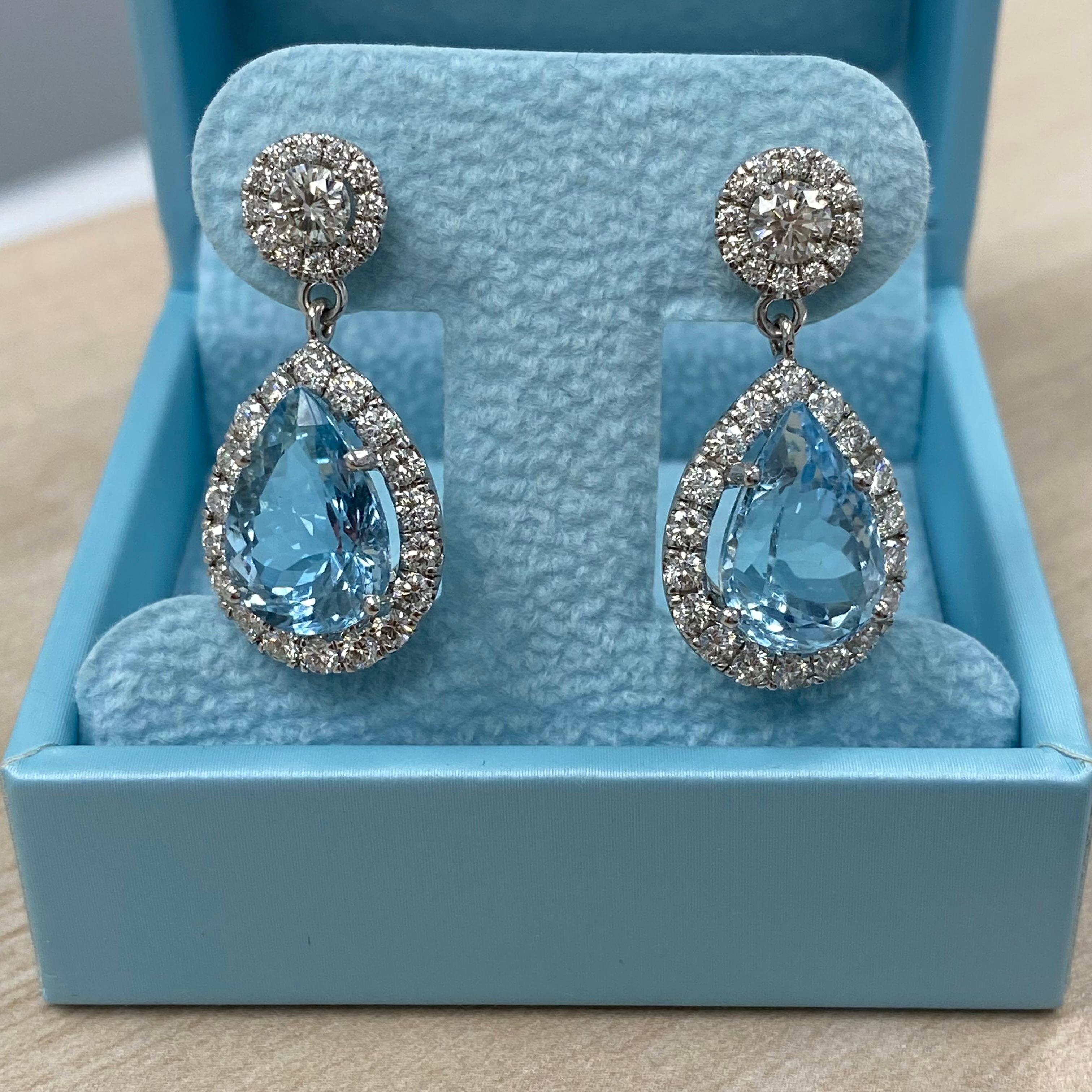 These stunning drop dangle earrings showcase a breathtaking pair of GIA-certified pear brilliant-cut blue aquamarines, weighing 4.36 carats and 5.03 carats respectively (GIA report number 6217272621). The aquamarines, with dimensions of 13.52 x 9.63