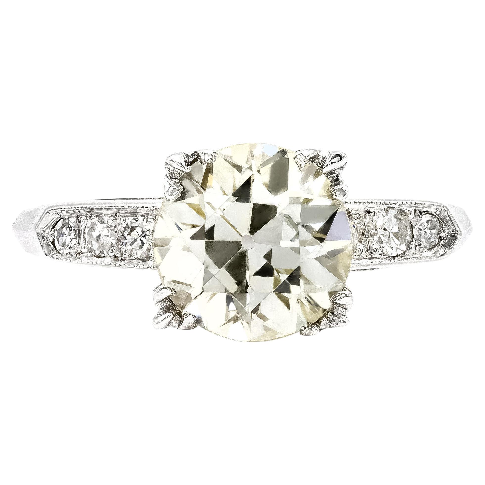 Say hello to this quintessential Deco era engagement ring. The 2 carat European diamond center has all the charm you'll need. Graded Q color you'll pick up on its warmer honey tone. The setting is made complete by diamond accented shoulders and a
