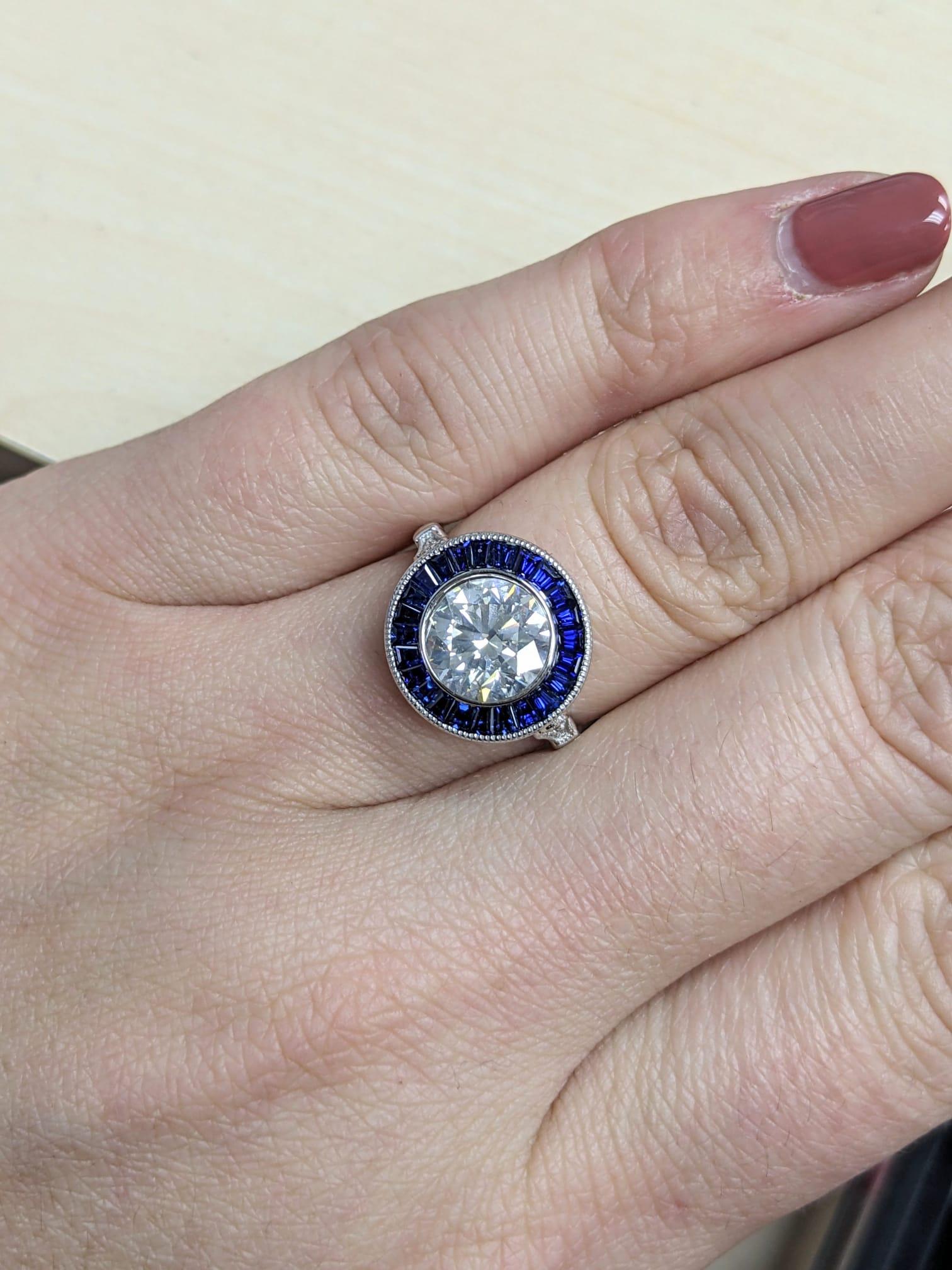 Cette bague de style Art déco est ornée d'un diamant vivant et substantiel de 2,20, entouré d'un anneau glamour de saphirs naturels d'un bleu royal. Certifié par le GIA avec des notes excellentes dans toutes les catégories de finition, le diamant