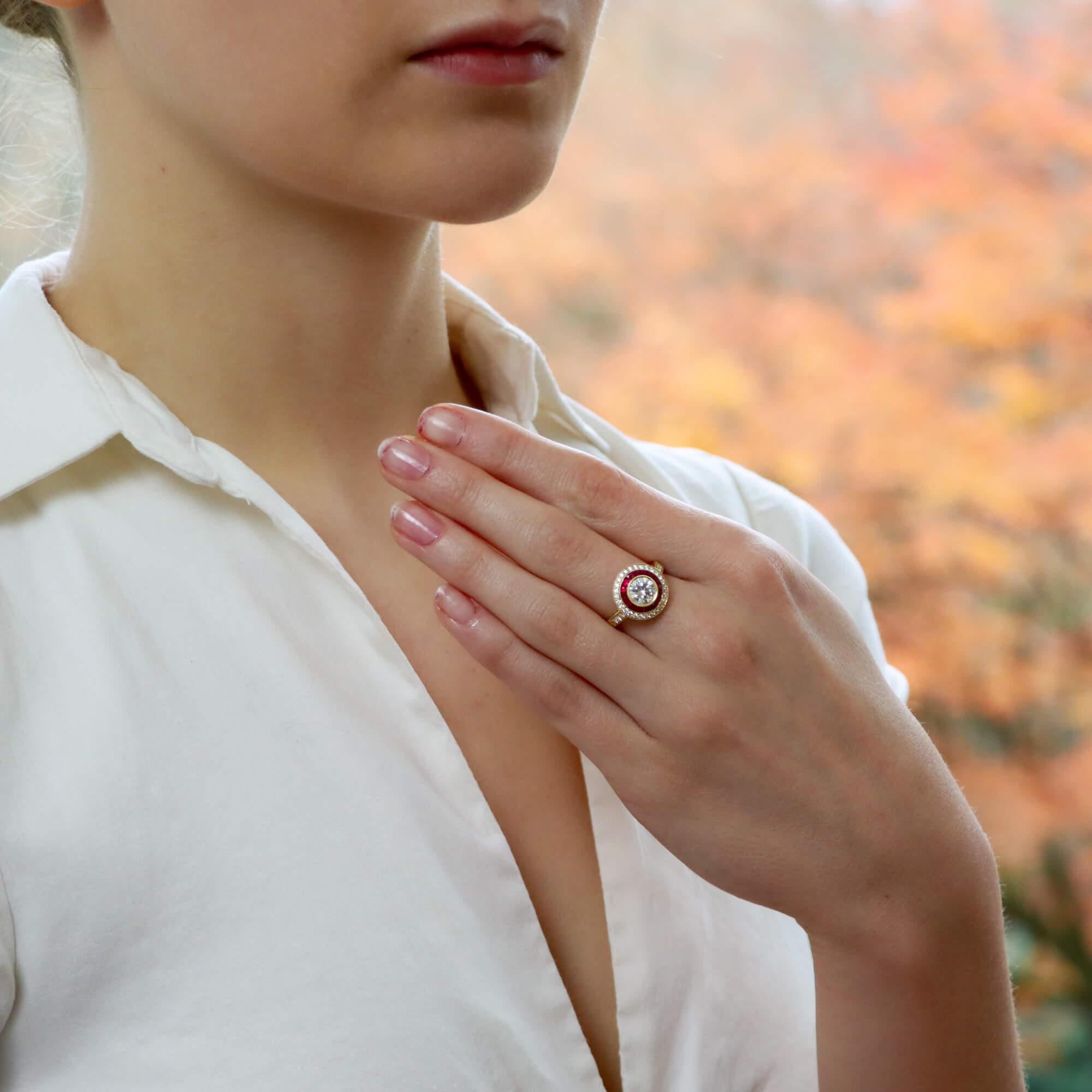 A beautiful Art Deco style ruby and diamond double target engagement ring set in 18k yellow gold.

The ring is predominantly set with a sparkly certified round brilliant cut diamond which is bezel set securely to center. Surrounding this beautiful