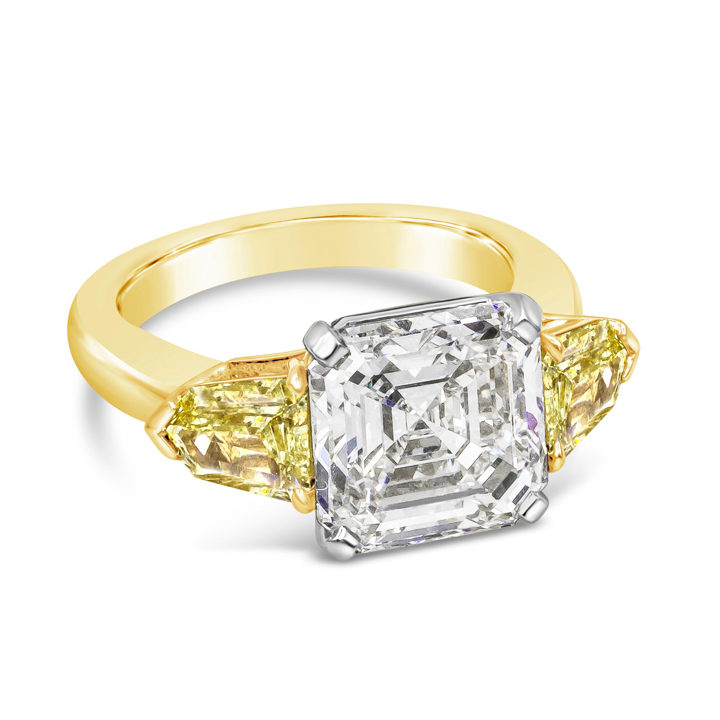 A stunning engagement ring, showcasing a 5.05 carats Asscher cut diamond certified by GIA as G color and VS2 clarity, set on a four prong basket made of platinum. Flanked by epaulette cut yellow diamonds weighing 0.81 carat total. Finely made with