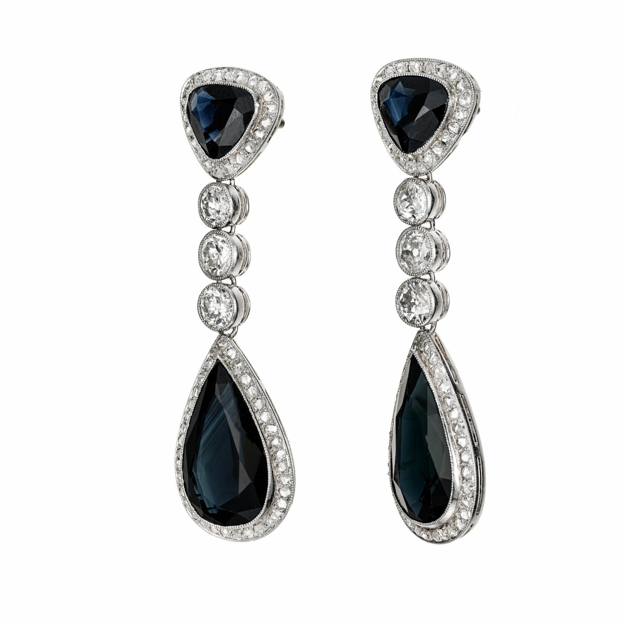 1915 Dramatic sapphire and diamond dangle drop earrings. 2 triangular shaped sapphires each with a halo of diamonds. 2 pear shaped sapphires each with a halo of diamonds hanging from a row of three old mind cut diamonds. The settings are original