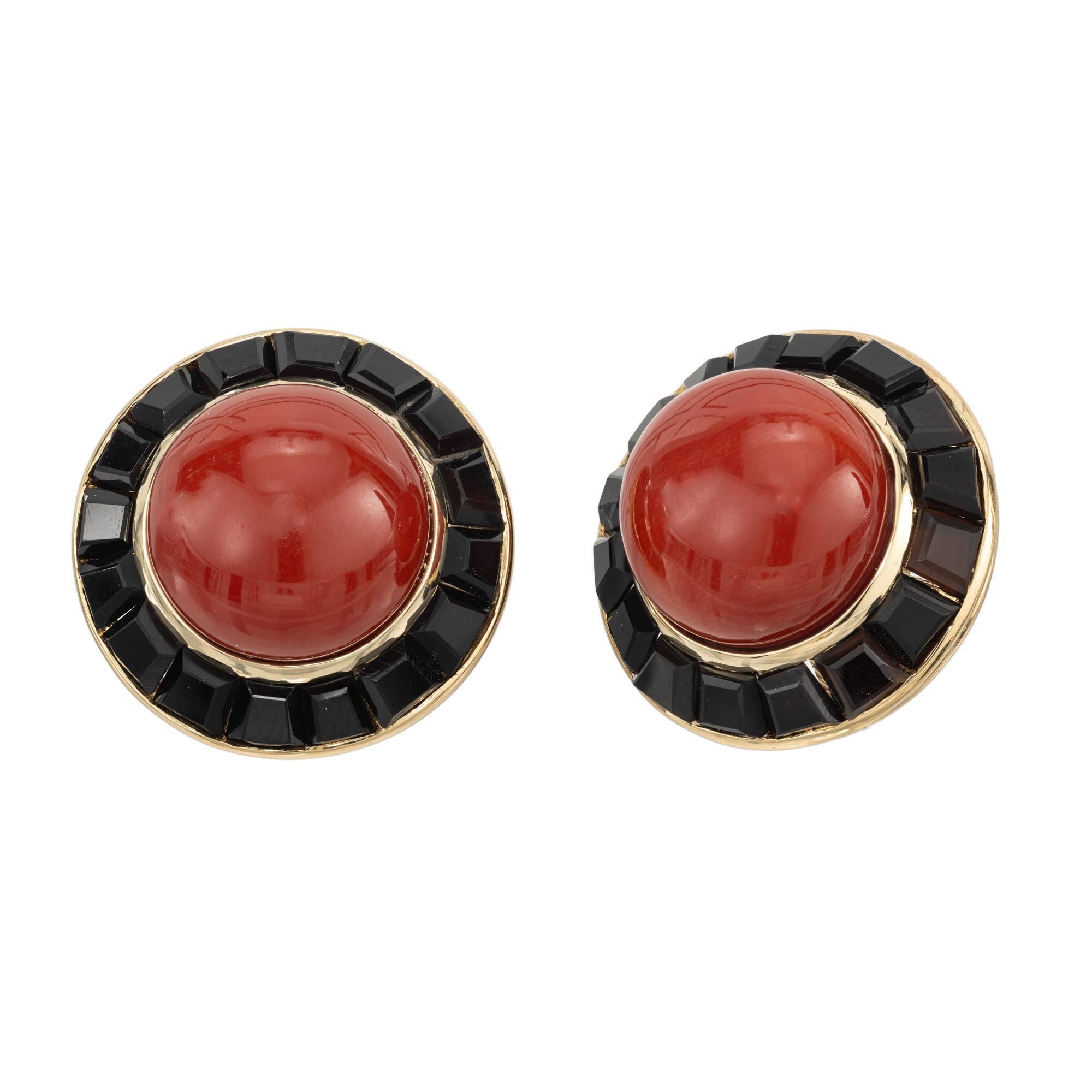 1950's coral and onyx earrings. 2 deep red round cabochon coral set in 18k yellow gold settings. Each coral is highlighted with 16 trapezoid cut onyx. The coral centers are well-polished untreated and the red hue of the coral contrasts beautifully