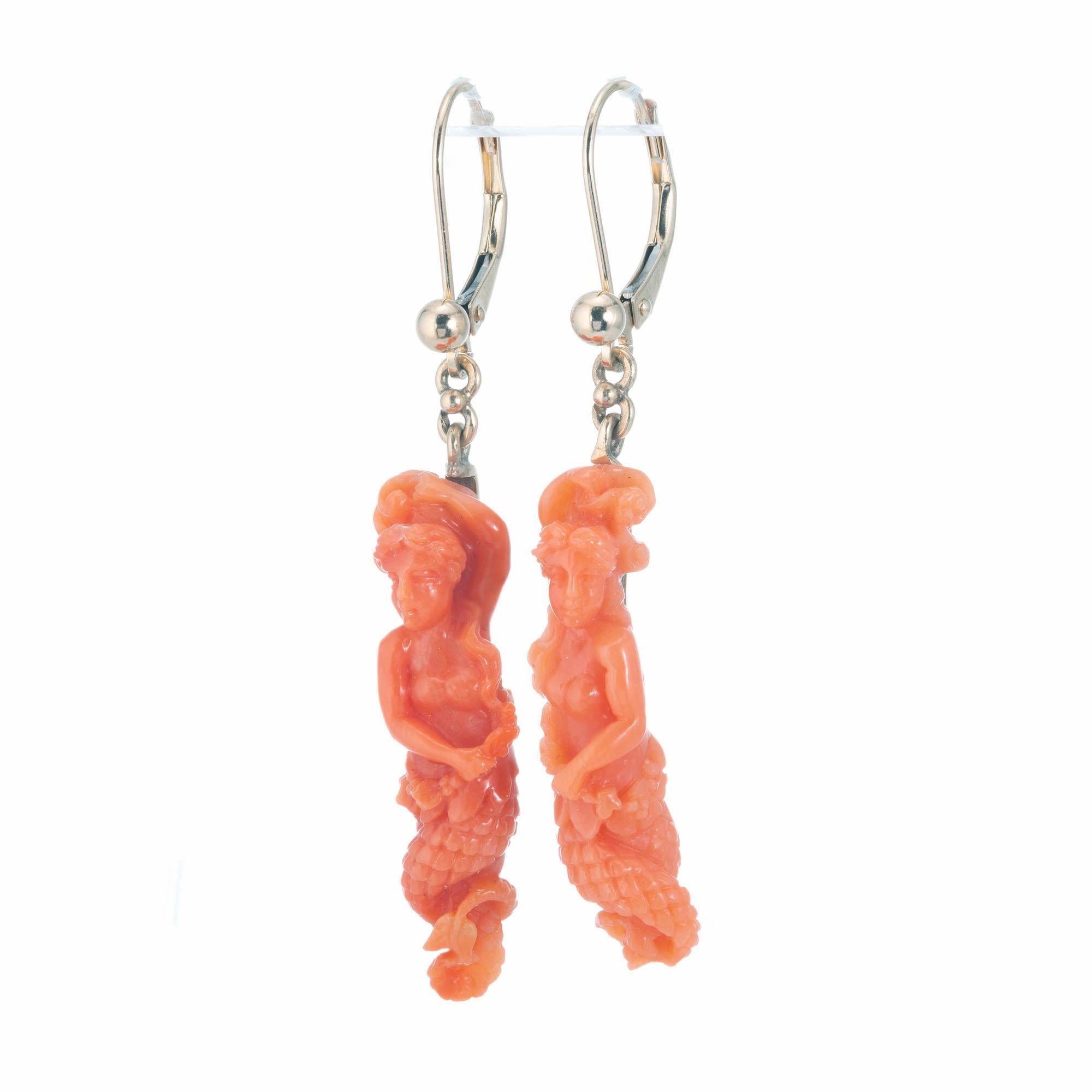 Carved 1900's mermaid natural GIA certified coral dangle earrings in 14k yellow gold. 

2 pierced orange coral mermaid carving GIA certificate # 2205747034
14k yellow gold 
Stamped: 14k 
4.9 grams
Top to bottom: 40.5mm or 1.5 Inch
Width: 7.5mm or