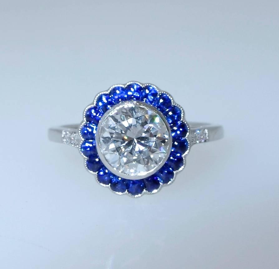 1.21 ct round brilliant cut diamond, GIA certified F (colorless) and slightly included to the first degree (SI1).  The bright blue natural sapphires surrounding this well cut diamond are all well matched and a bright blue.  The ring is platinum and