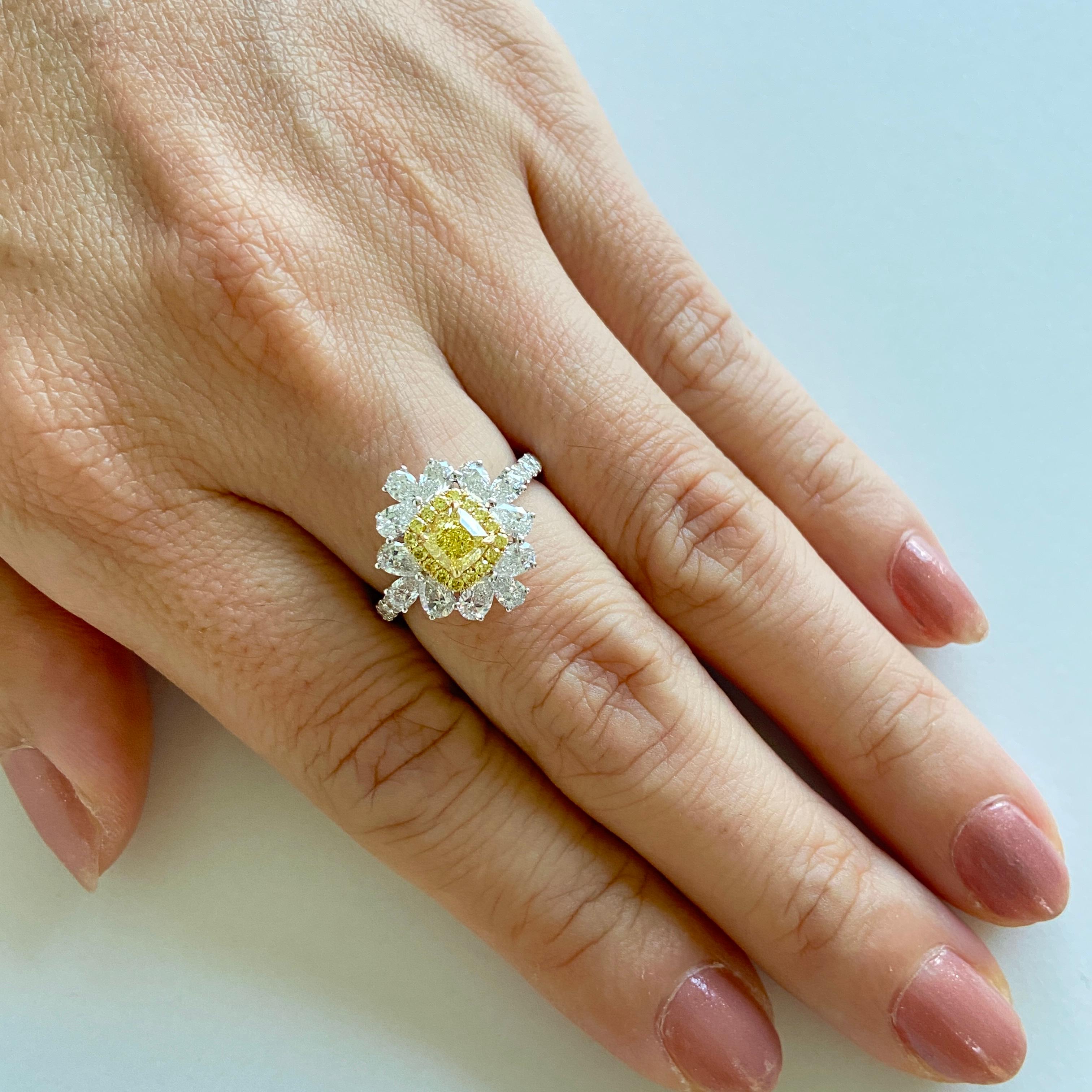 Dieser wunderschöne Ring mit einem schillernden gelben Diamanten verkörpert die Essenz der Raffinesse. Der Kissen-Diamant, ein sonnenbeschienenes Wunderwerk, ruht auf einer goldenen Umarmung, die einen Zauber zeitloser Eleganz