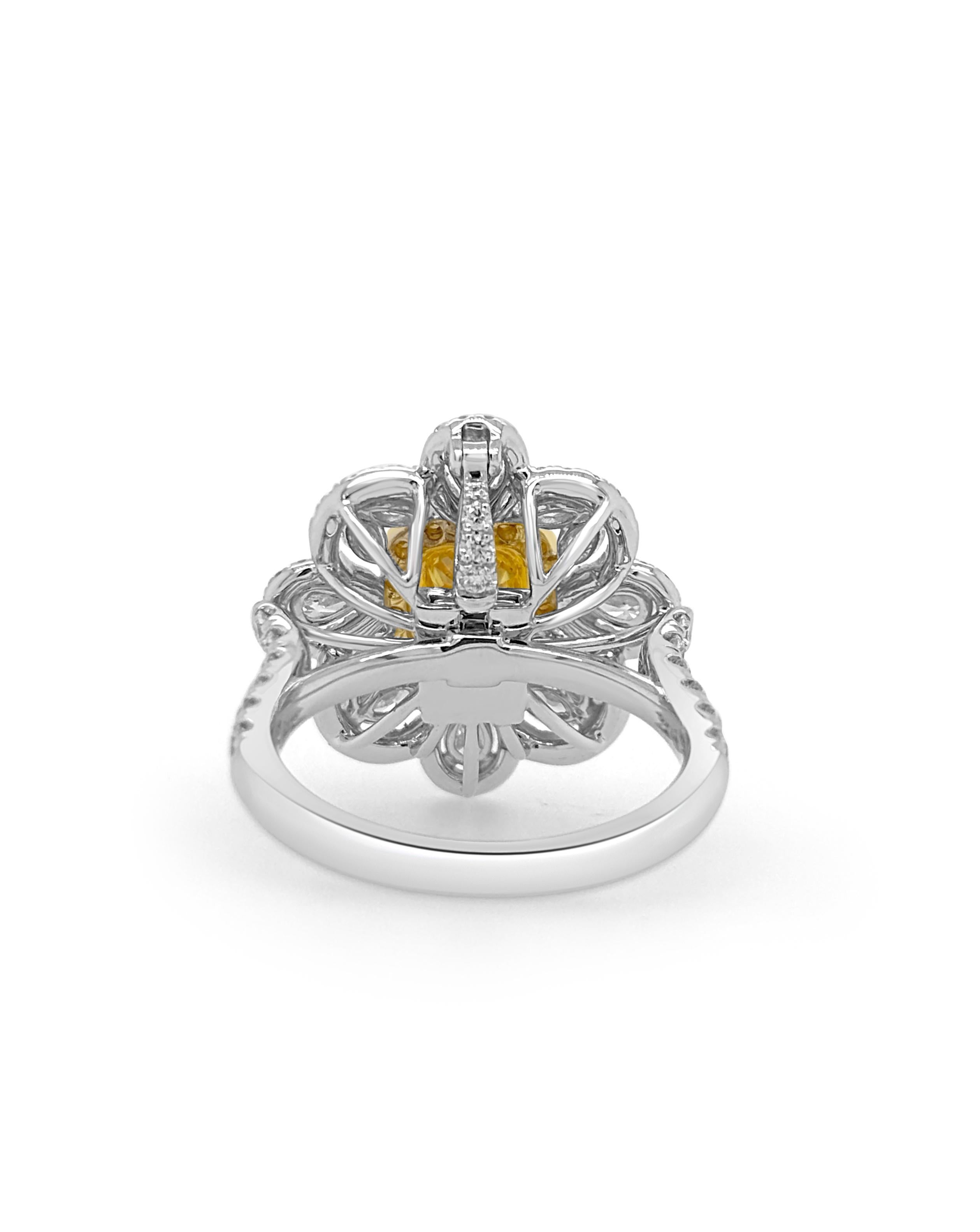 Cette magnifique bague présente en son centre un diamant jaune coussin naturel certifié par la GIA, entouré de diamants blancs naturels étincelants disposés dans un élégant motif en forme de fleur. Réalisé en or 18 carats, il dégage un charme