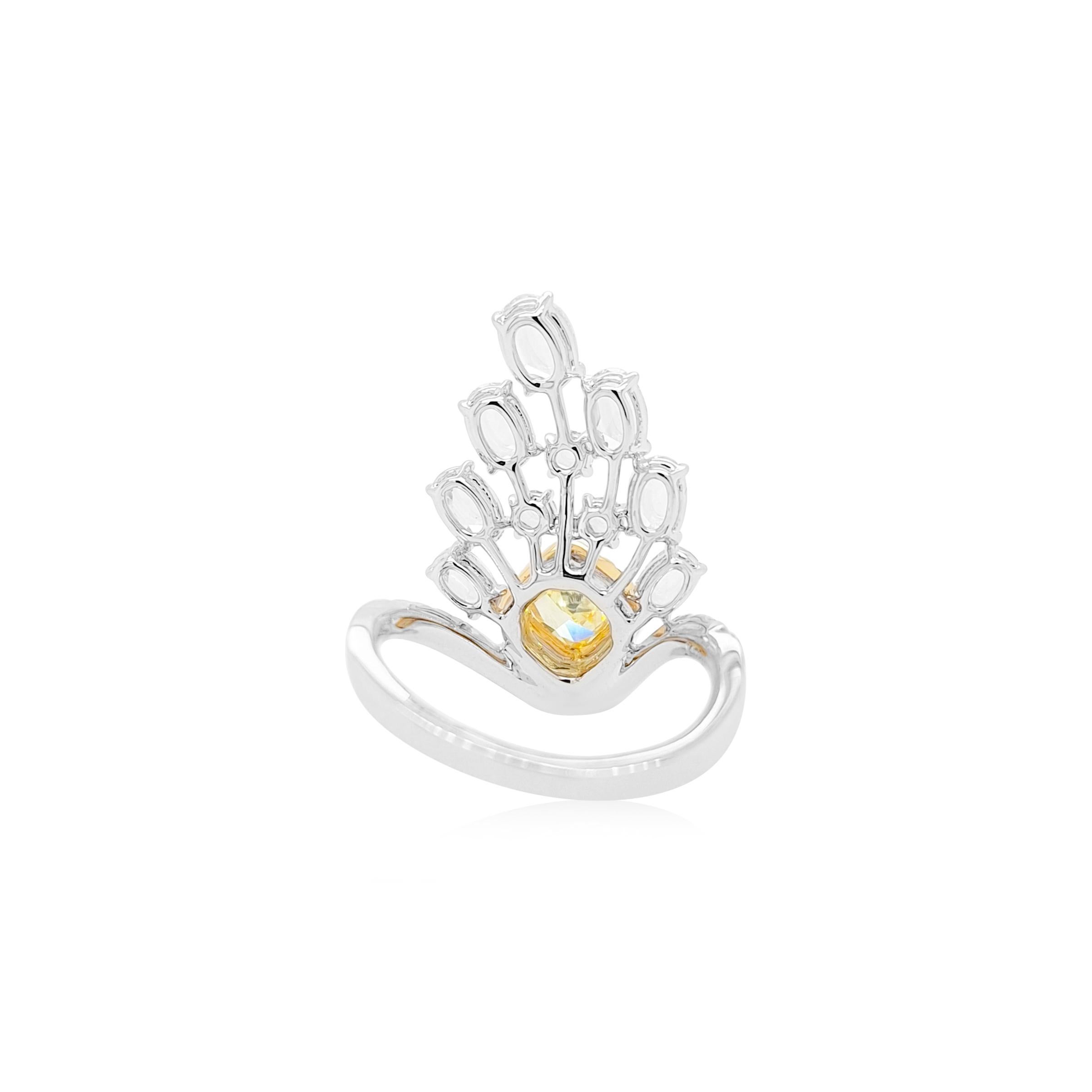 Un luminoso diamante amarillo talla cojín ocupa el centro del escenario, exudando una sofisticación atemporal. 
Está acentuada por una matriz en forma de pluma de diamantes blancos talla rosa, cuyo delicado destello realza el brillo de la piedra.