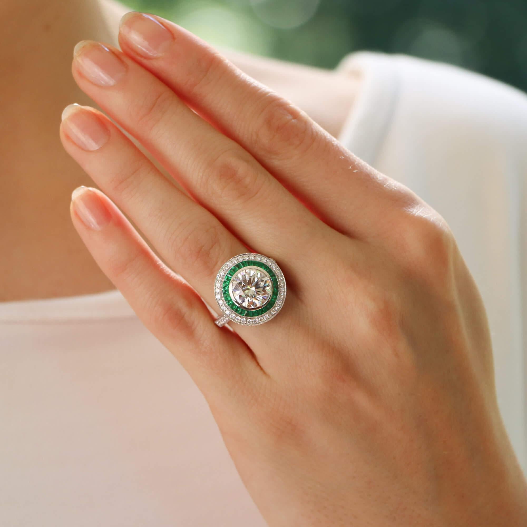 Un precioso anillo de doble diana de esmeraldas y diamantes estilo Art Decó certificado por el GIA y engastado en platino.

En el anillo predomina un brillante diamante redondo de talla brillante certificado por el GIA, engastado en bisel en el