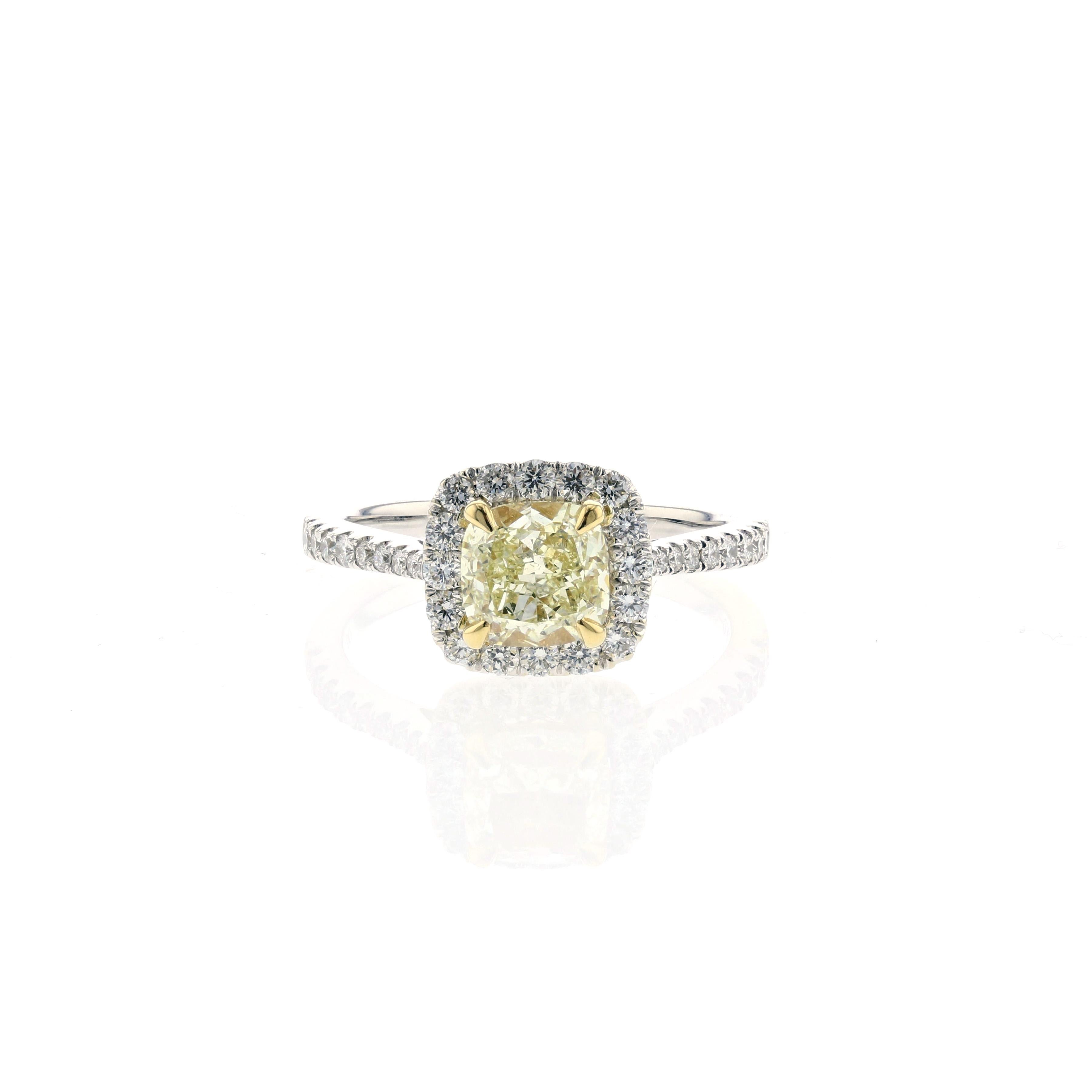 Engagement ring in 18K white gold featuring a cushion-cut yellow diamond that is halo set by round brilliant-cut diamonds and round diamonds down the band.  The center diamond totals 1.55 carats; GIA certified as a W-X color and VS1 clarity.  In