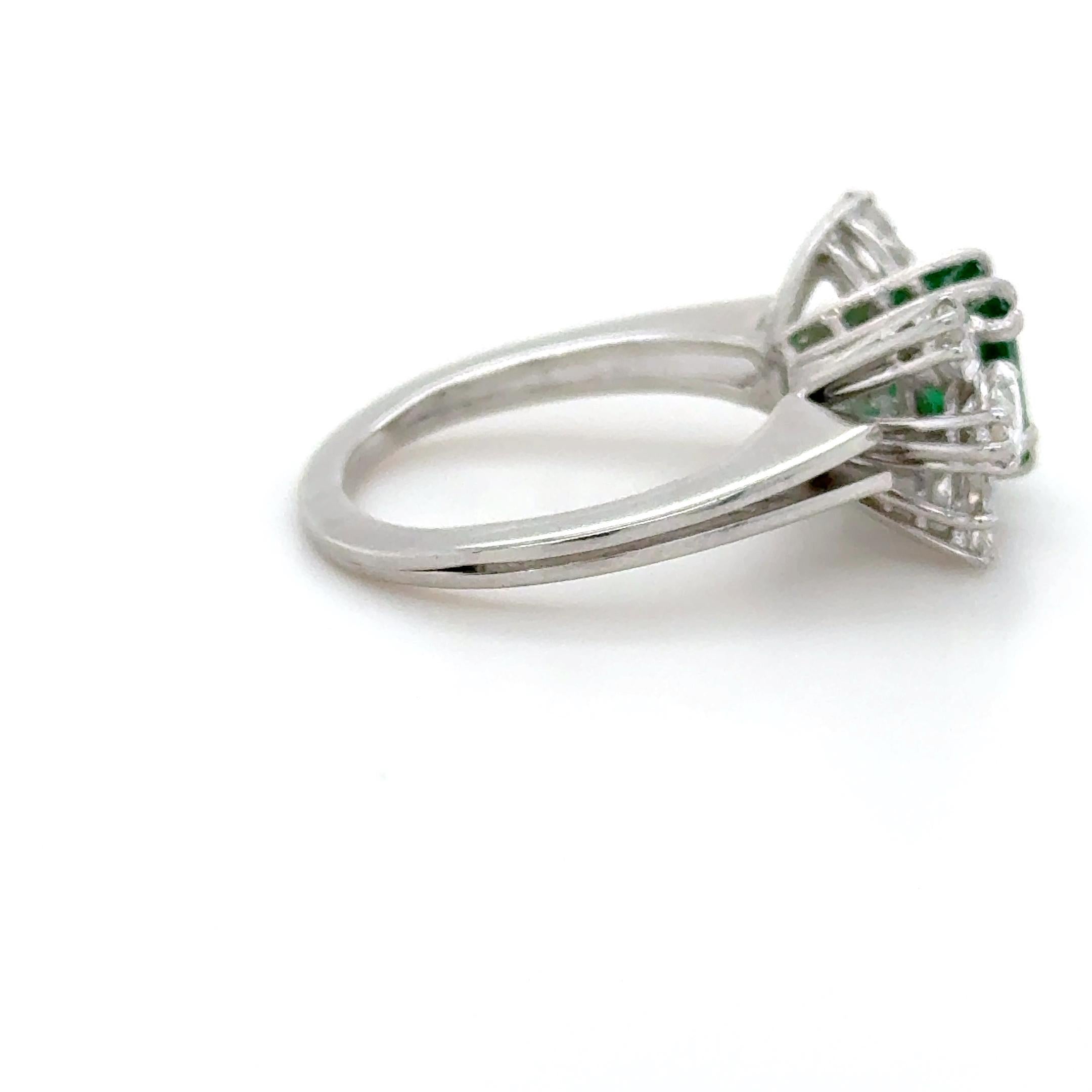This absolutely stunning ring, boasts a gorgeous 1.00 carat emerald and measuring 6.24 x 5.87 x 3.34 mm. Flanked by six top quality marquise cut diamonds weighing 1.50 carats total. Mounted in platinum and beautifully made, this ring is a
