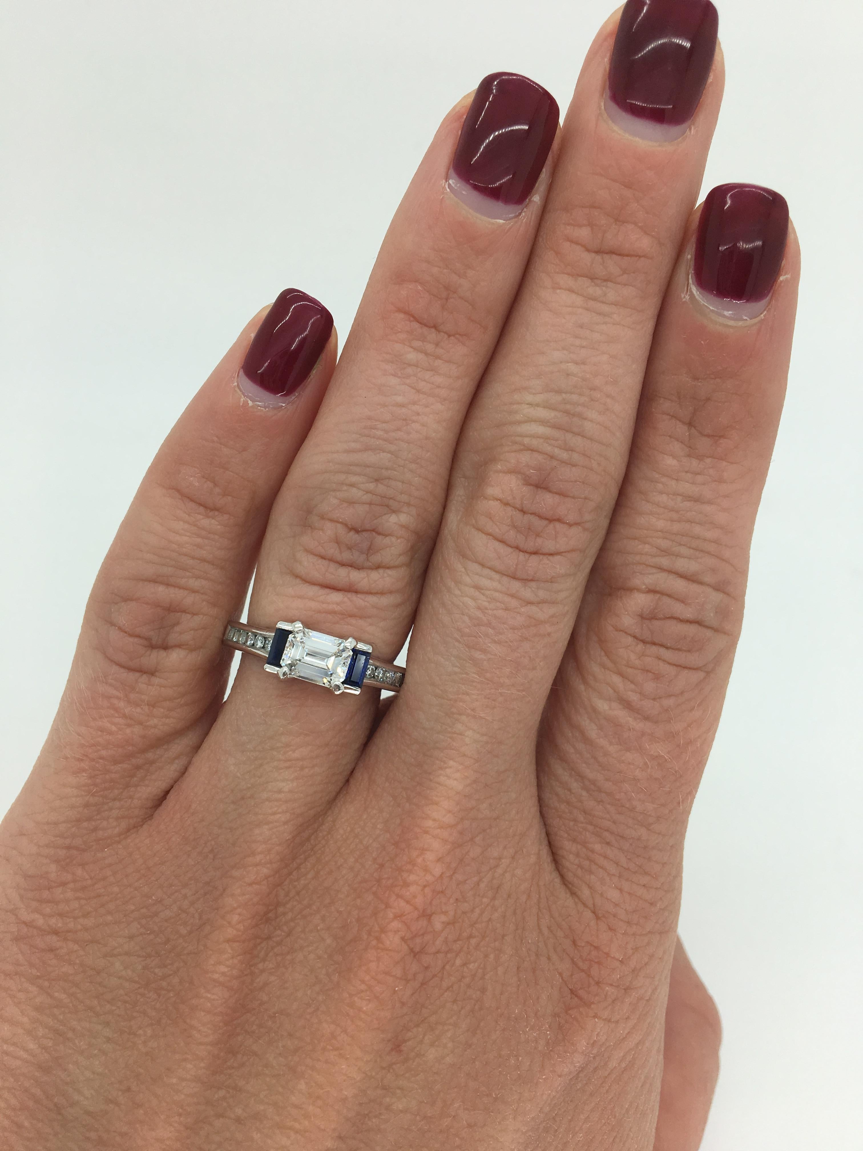 This unique ring features a GIA Certified .90CT Emerald Cut Diamond accenting the featured diamond are two beautiful blue sapphires. 

GIA Certified: Certification # 10827078
Center Diamond Carat Weight: .90CT
Center Diamond Cut: Emerald Cut
Center