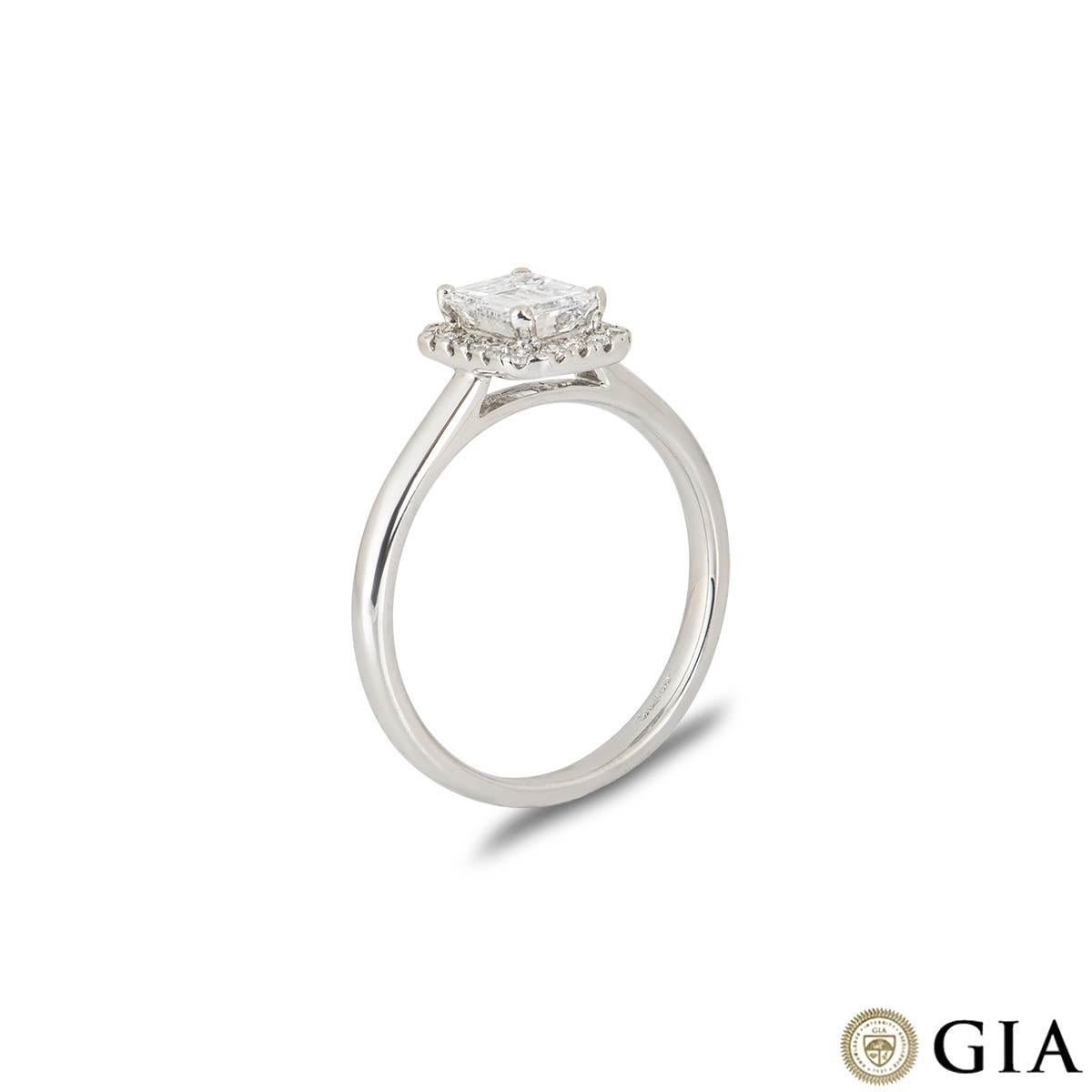 A classic 18k white gold diamond solitaire engagement ring. The ring is set to the centre with an emerald cut diamond weighing 0.74ct, colour D and VS2 clarity complemented by a round brilliant cut diamond cluster totalling 0.13ct, well matched in