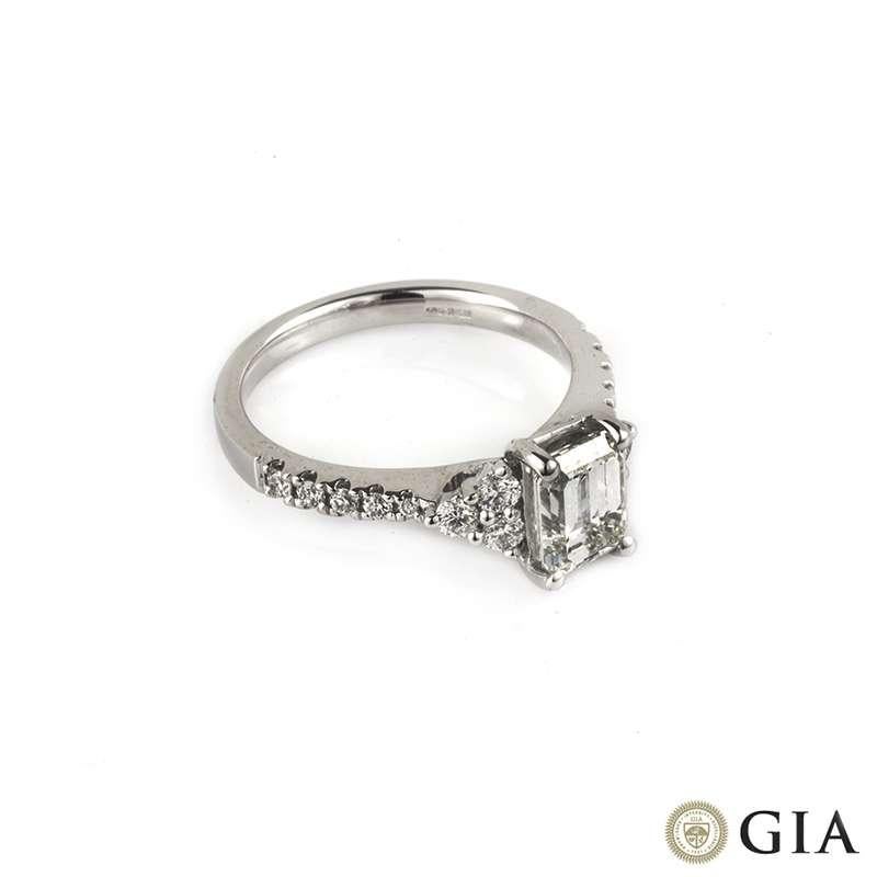 An emerald cut diamond ring in 18k white gold. The central 1.33ct diamond is G colour, VS1 clarity and is set between a cluster of 3 round brilliant cut diamonds on each side, along with diamond set shoulders totalling 0.37ct. The ring is currently