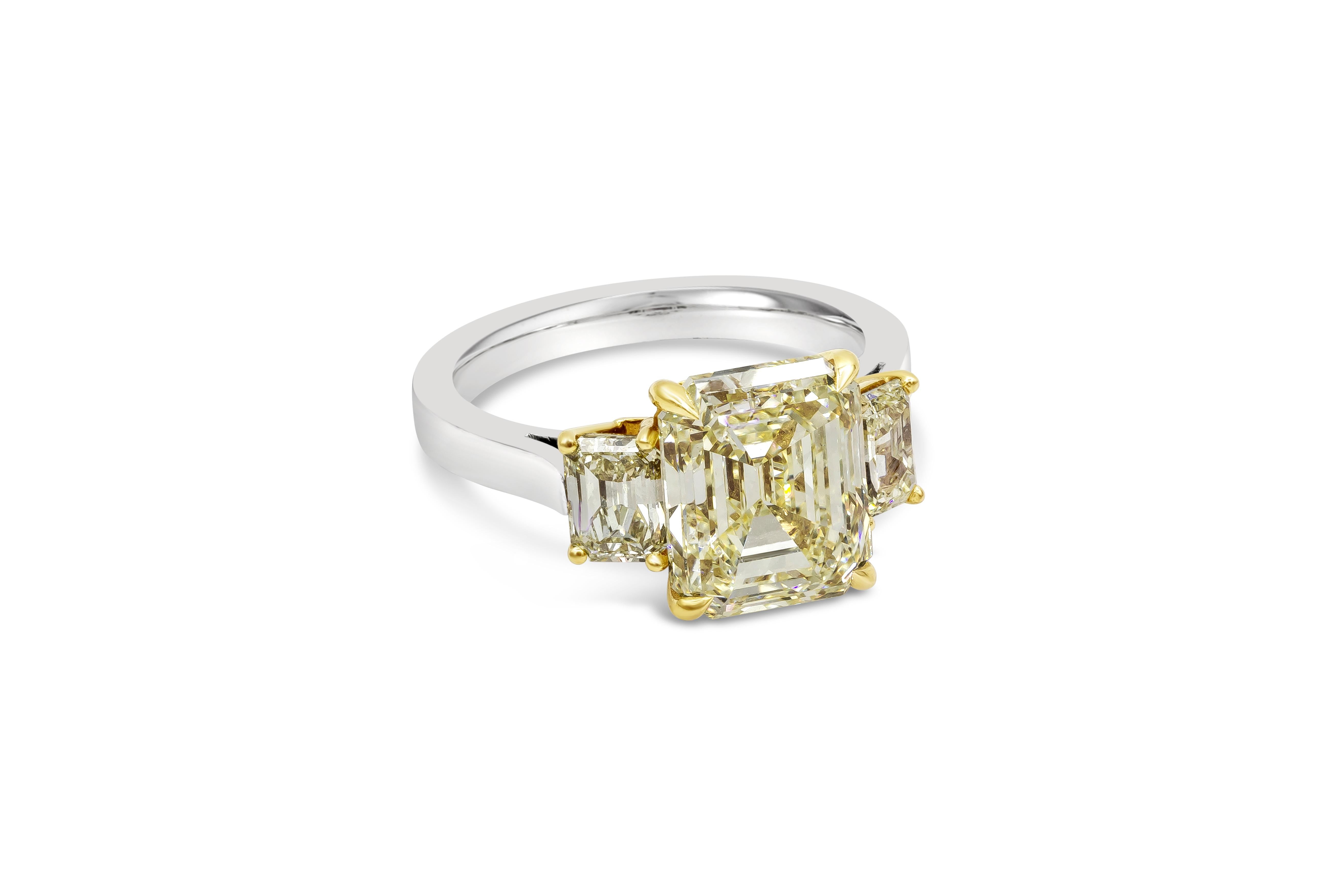 Une bague de fiançailles rare et spectaculaire mettant en valeur un diamant central de 5,17 carats de taille émeraude certifié par le GIA comme étant de couleur jaune fantaisie et d'une pureté VS1. Deux petits diamants jaunes fantaisie de taille